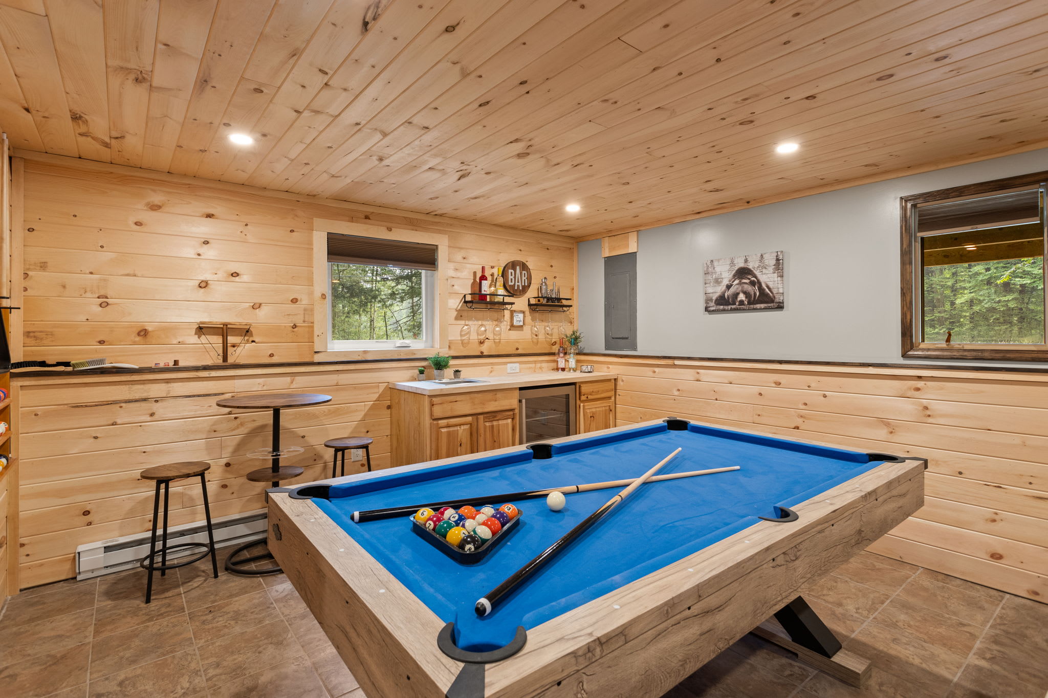 Rustic Game Room & Bar – A stylish entertainment space featuring a classic blue pool table, warm wood-paneled walls, and a cozy bar area for endless fun.