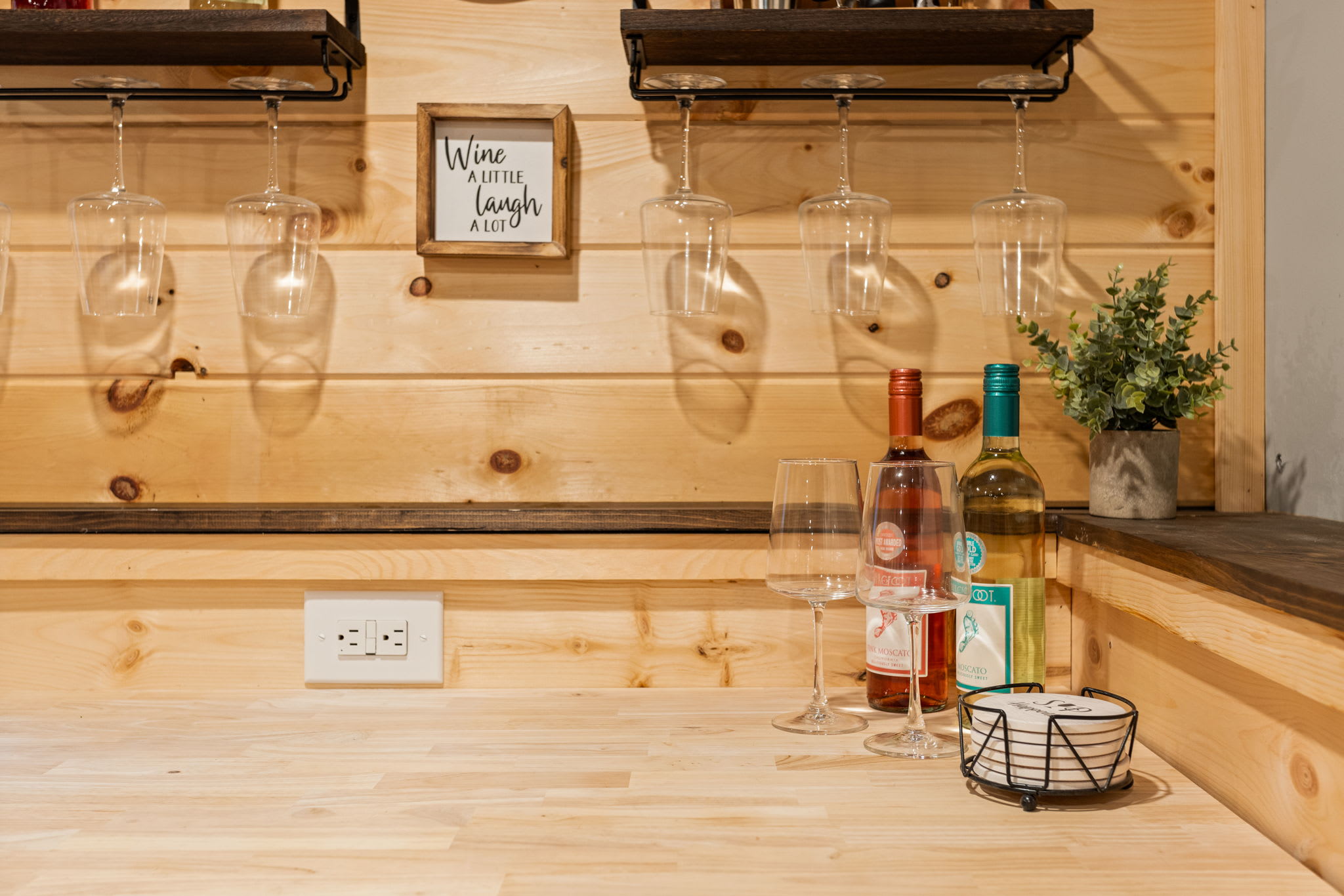 A close-up of the home bar featuring hanging wine glasses, stylish decor, and a warm, inviting atmosphere.