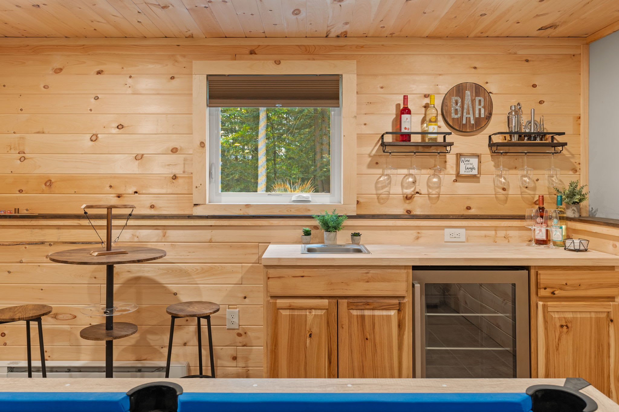 A charming home bar setup with wooden cabinetry, a mini fridge, and high-top seating for casual drinks and conversations.