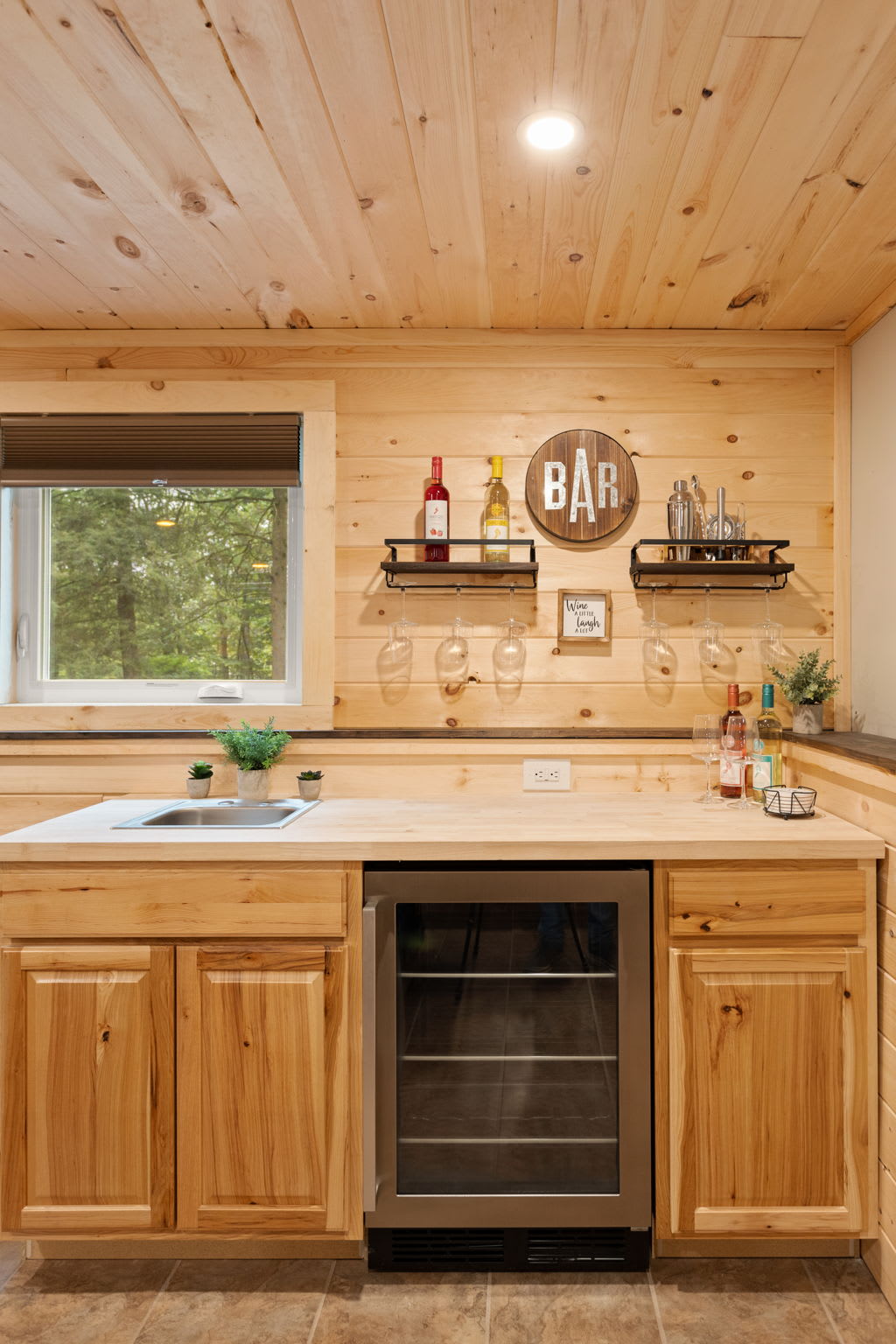 A well-organized bar area featuring floating shelves, a wine fridge, and rustic decor that enhances the cozy ambiance.