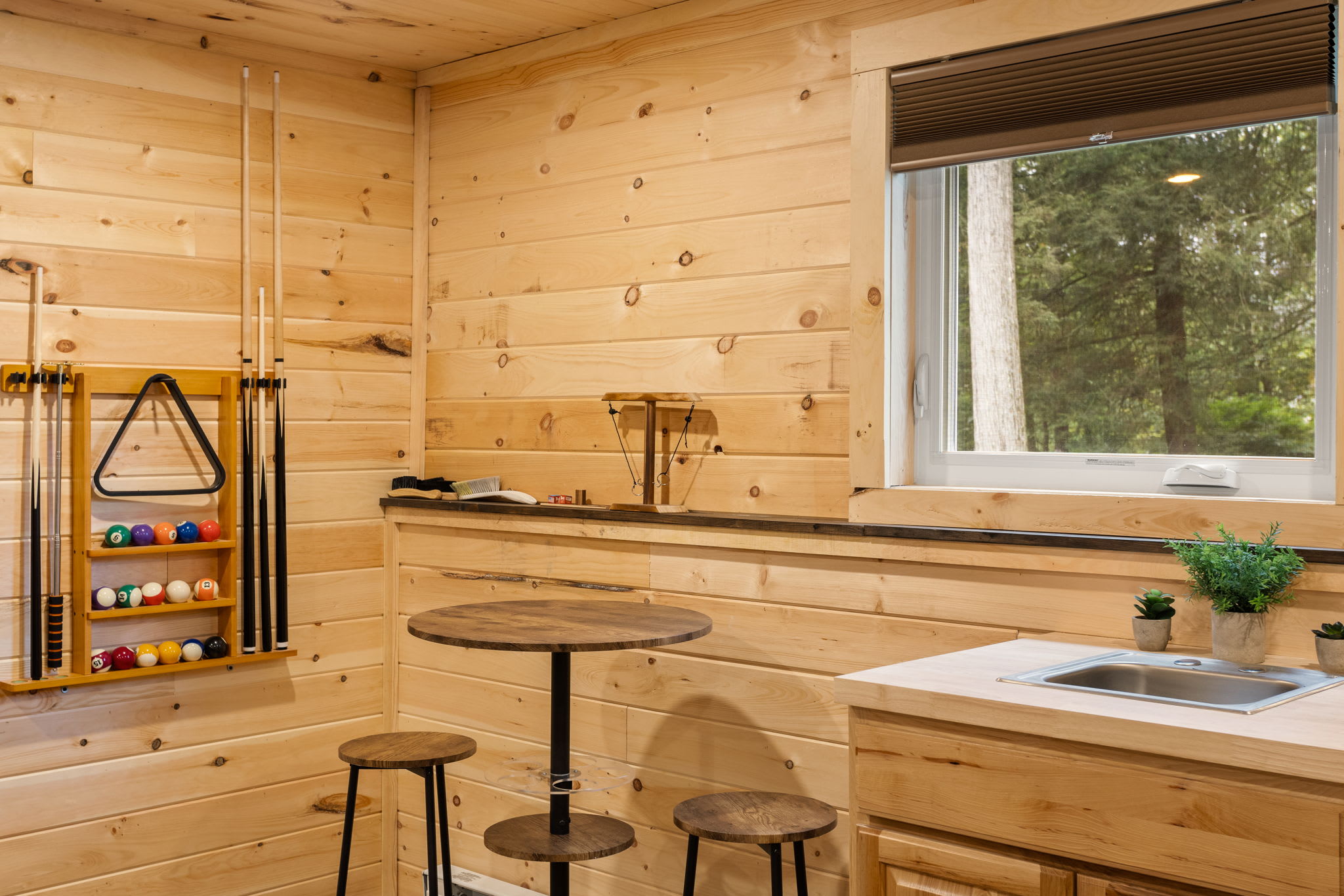 A thoughtfully designed game room featuring a built-in bar nook, window views, and the perfect mix of play and relaxation.