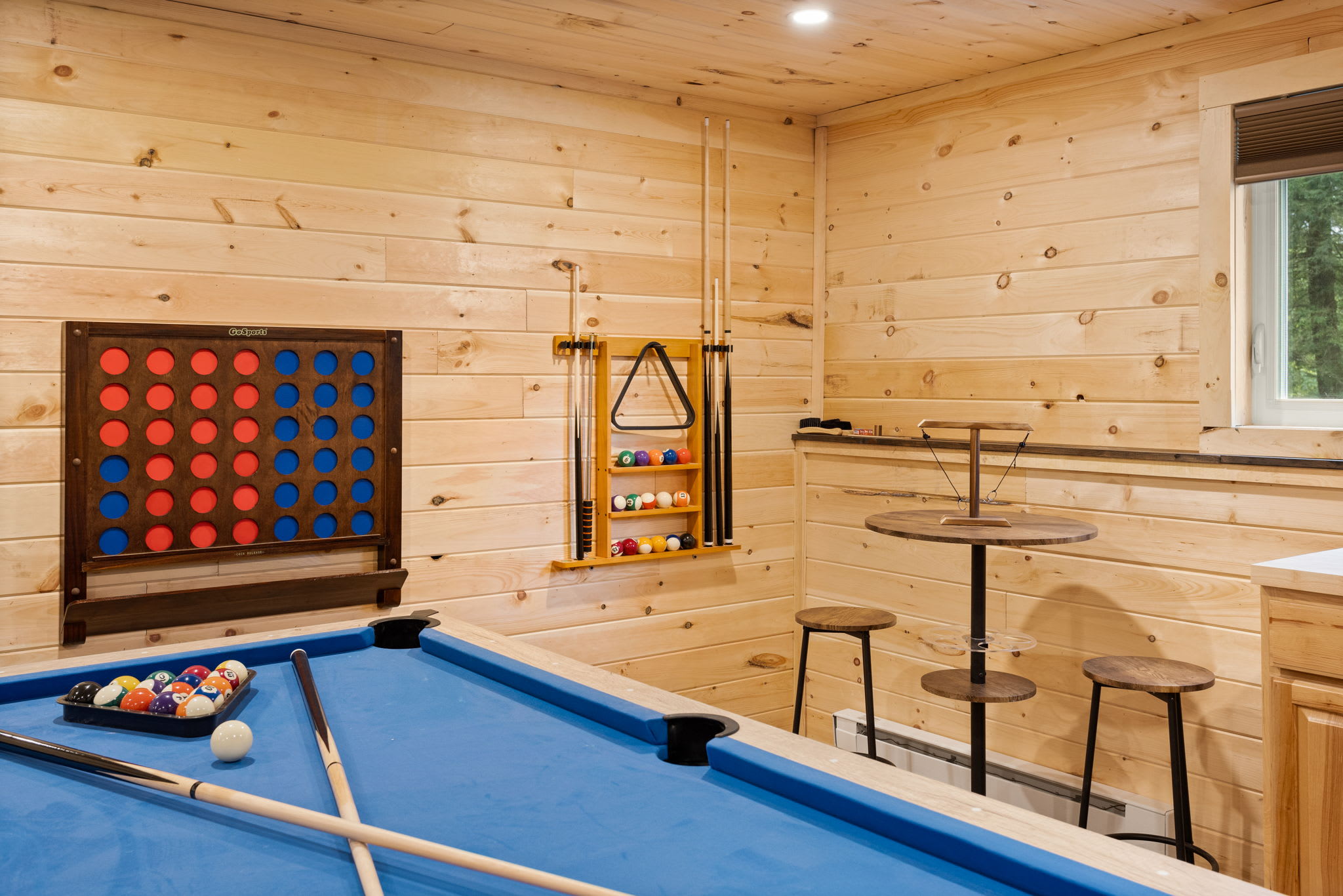 A well-organized entertainment area with a mix of classic games, high-top seating, and warm cabin-style decor.