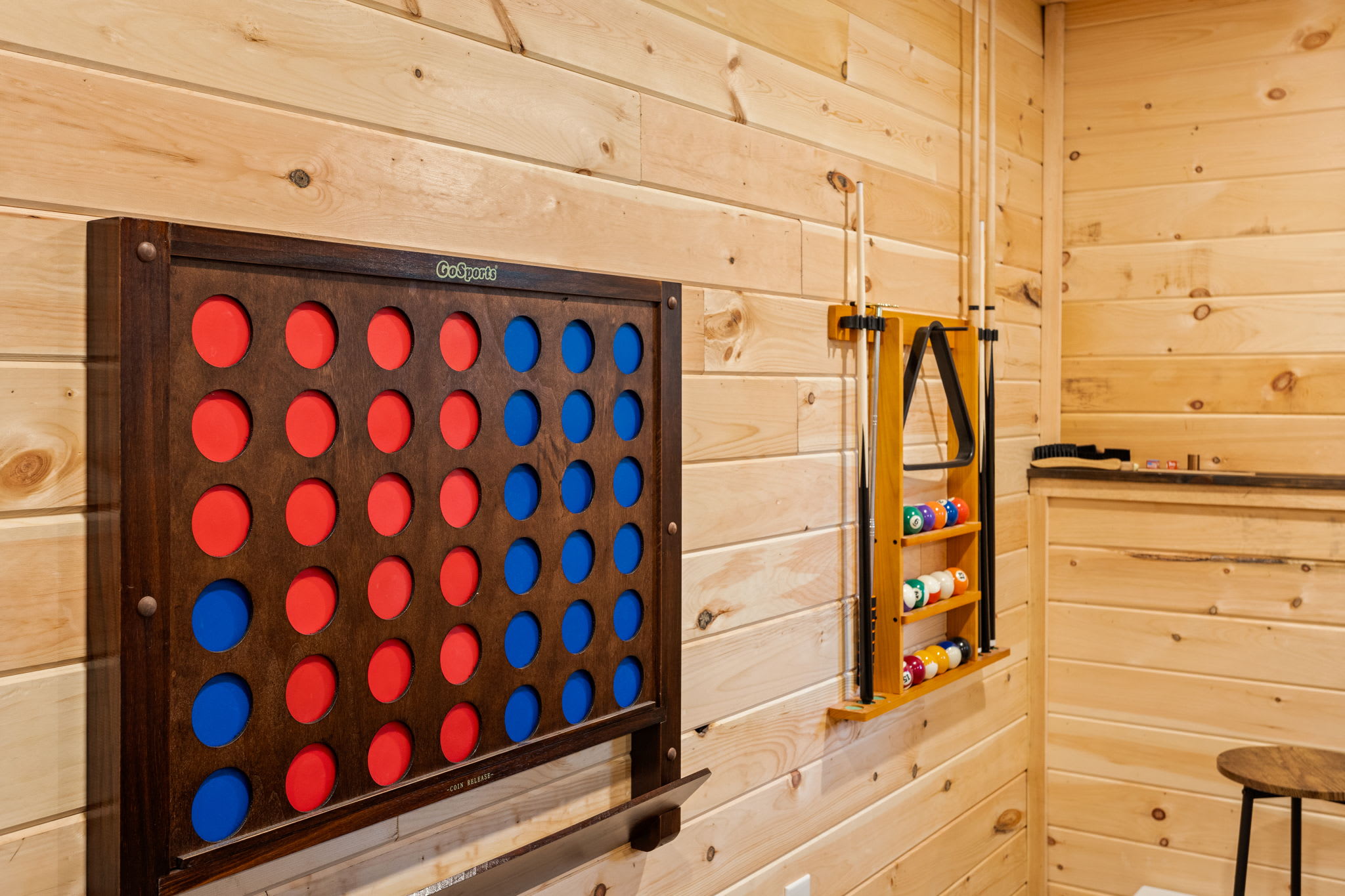 A playful and unique wall-mounted Connect Four game adds a fun twist to this rustic and stylish game room.