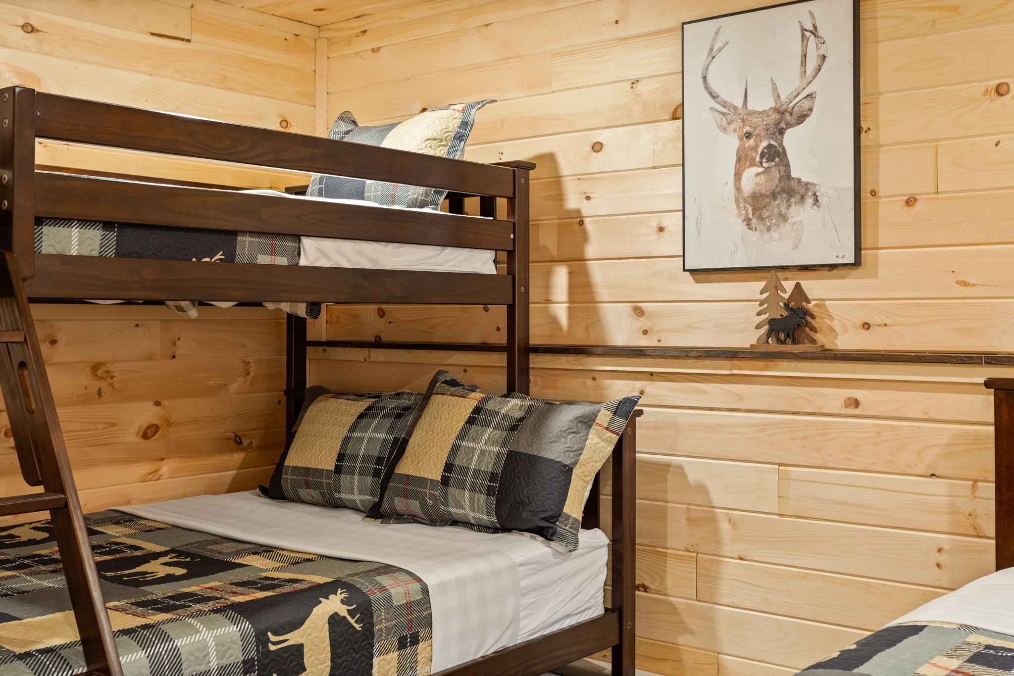 A charming cabin-style bedroom featuring a sturdy wooden bunk bed, cozy plaid bedding, and nature-inspired decor.