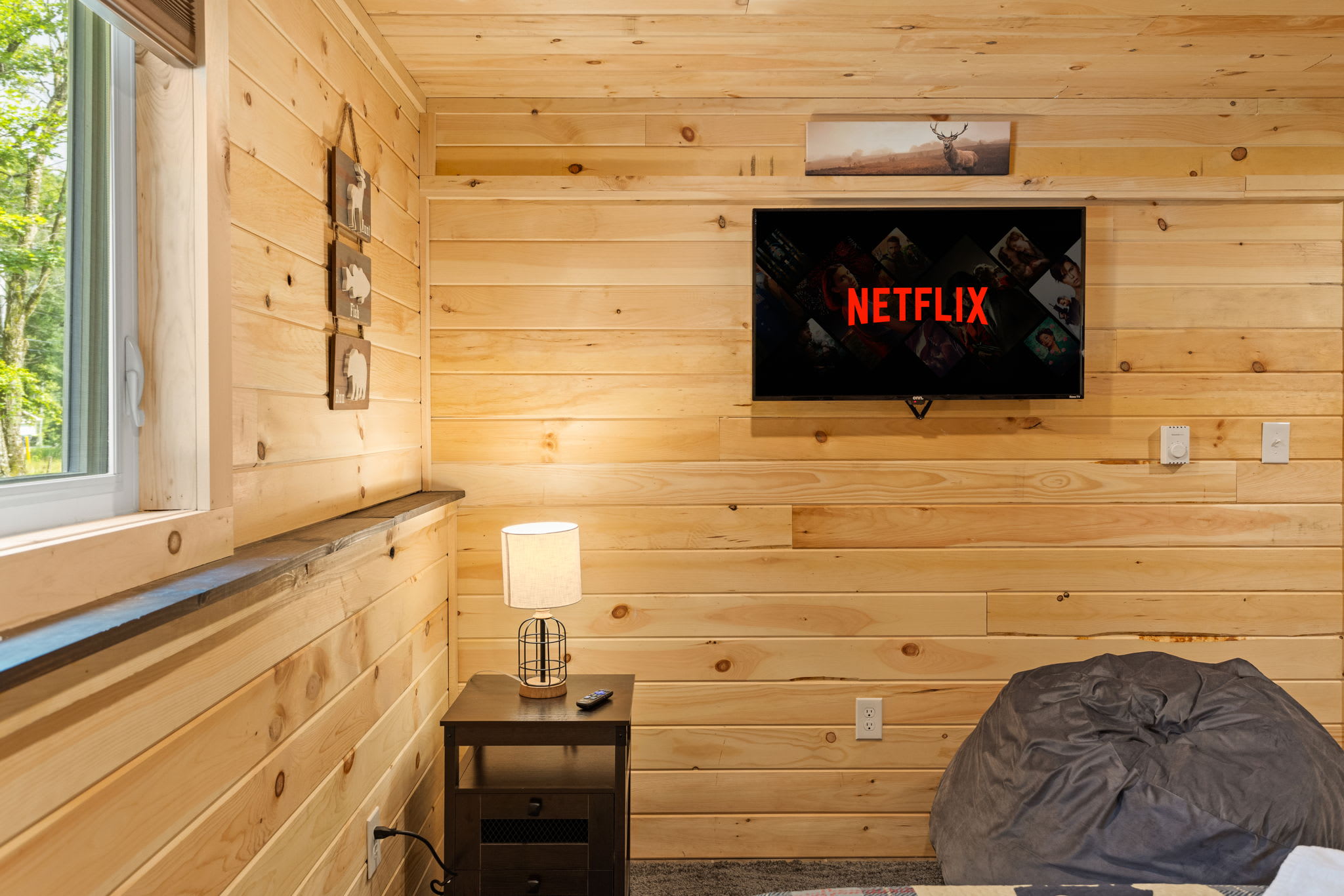 A thoughtfully designed sleeping space with a comfortable twin bed, soft lighting, and a wall-mounted TV for cozy nights in.