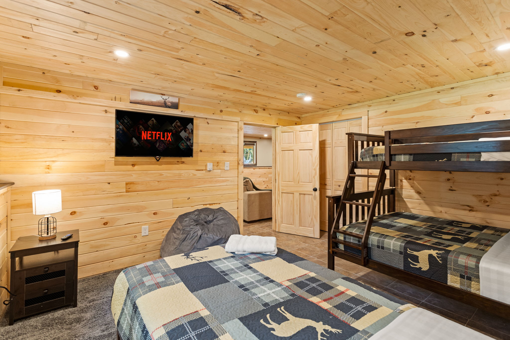 A spacious and inviting room with a mounted TV, plush seating, and a warm wood-paneled design for a true cabin experience.