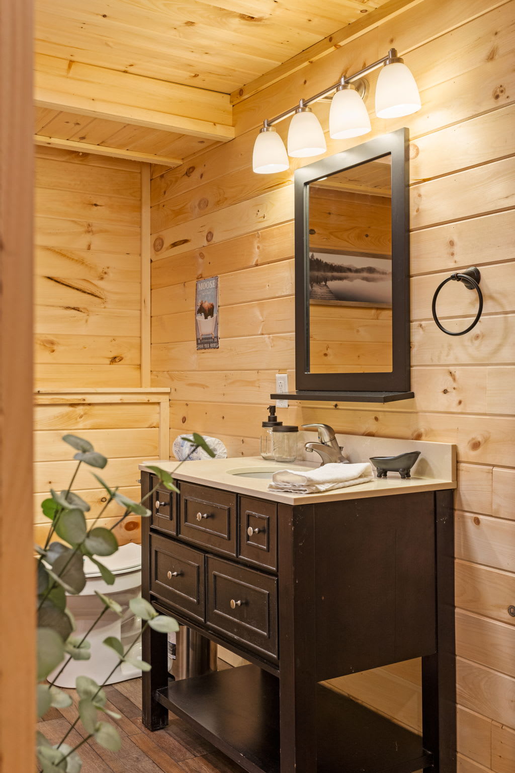 A beautifully designed bathroom featuring a dark wood vanity, soft lighting, and warm rustic accents for a relaxing experience.