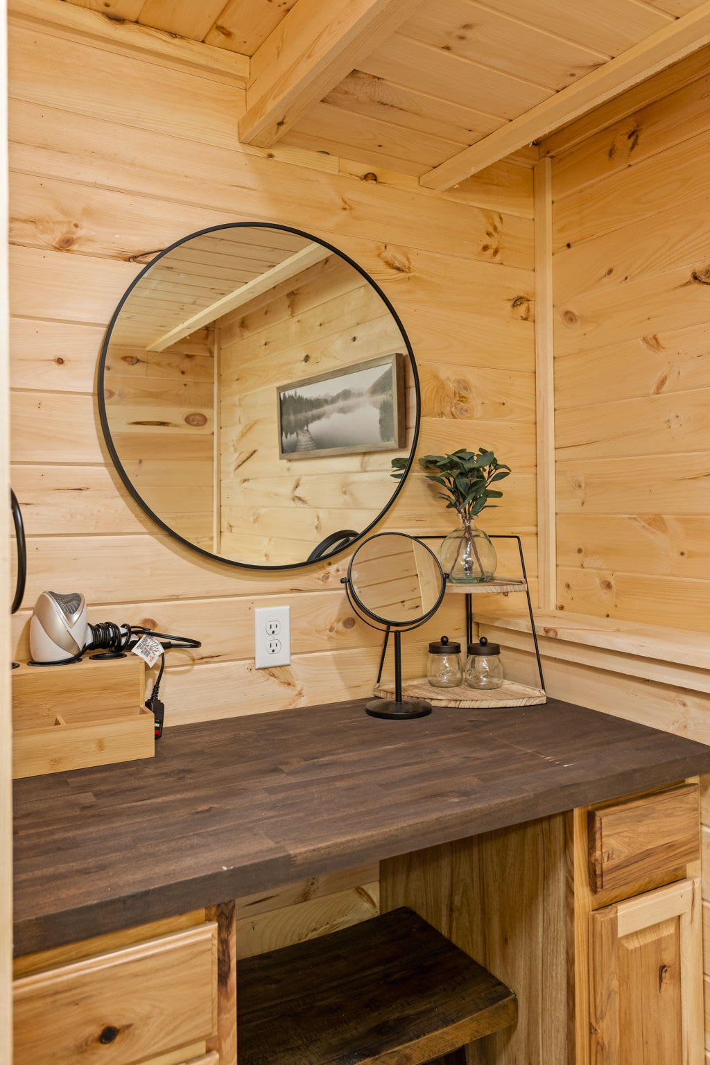 A rustic vanity area with a circular mirror, wood countertop, and warm lighting, creating a perfect space for getting ready.