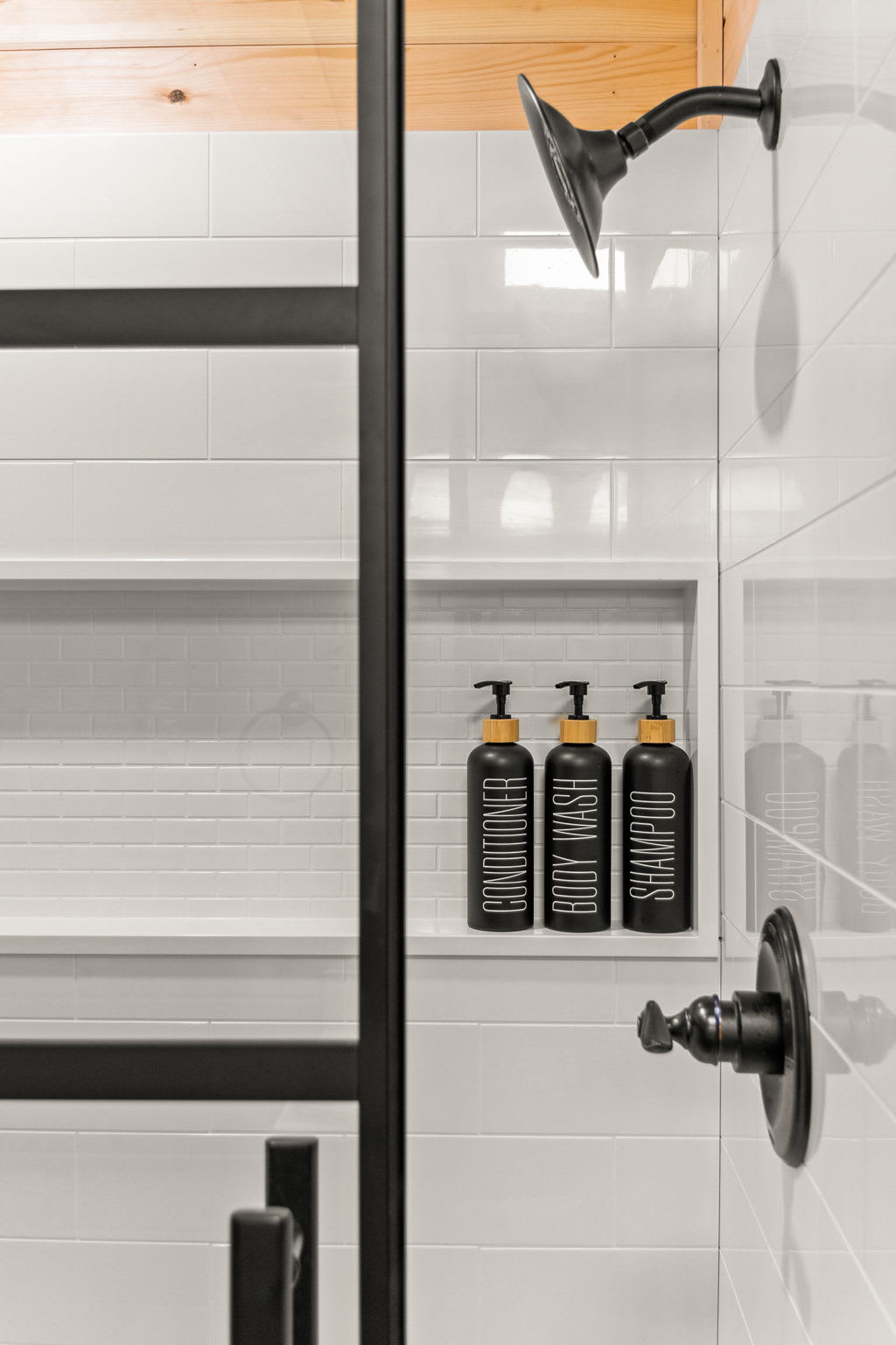 A close-up of a built-in shower nook with sleek black dispensers, offering convenience and style in a modern bath space.