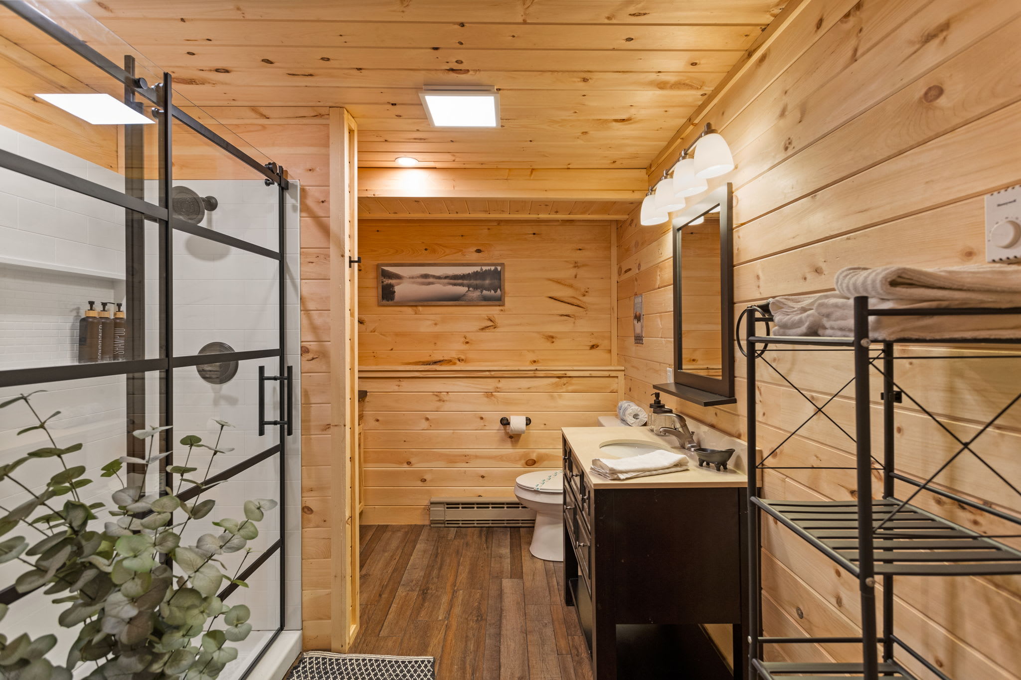 A well-organized bathroom with a walk-in shower, open shelving, and a perfect blend of modern and cabin-style elements.
