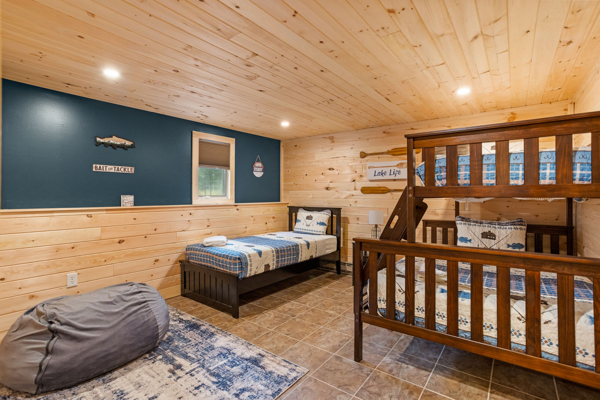 A beautifully designed bedroom featuring a mix of single and bunk beds, a soft blue accent wall, and plush seating for added comfort.