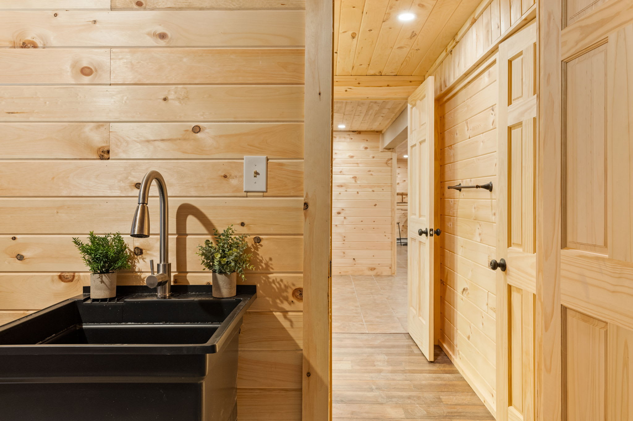 Rustic & Modern Utility Space – A sleek black farmhouse sink, warm wood tones, and stylish lighting make this functional area both practical and visually appealing.