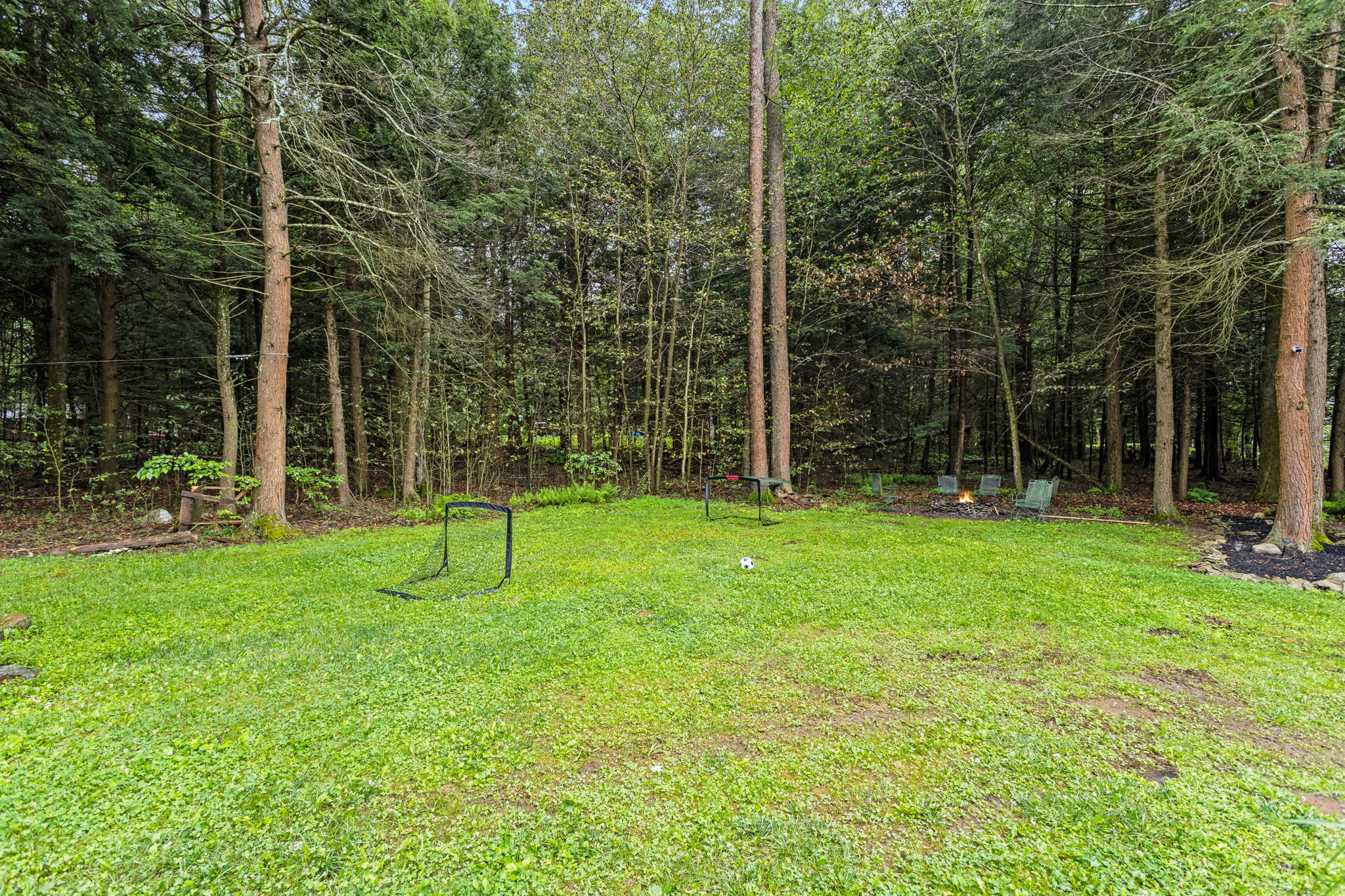 A spacious grassy area surrounded by trees, offering plenty of room for outdoor games and relaxation in a serene setting.