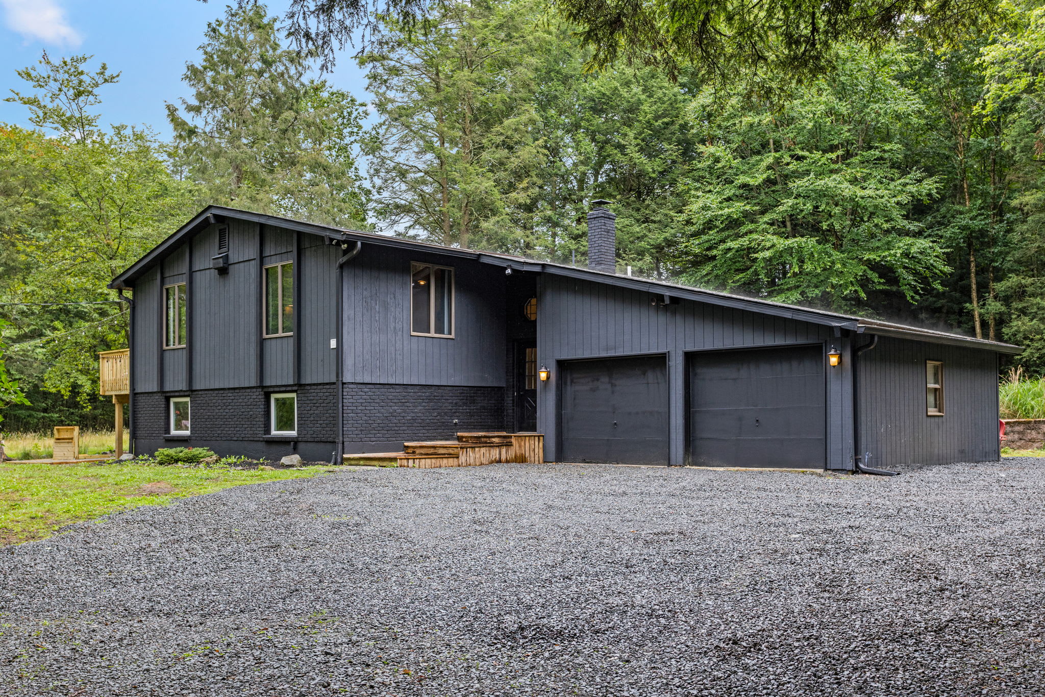 Modern Cabin with Ample Parking – A sleek black cabin with a spacious driveway, surrounded by lush greenery and offering a secluded yet stylish retreat.