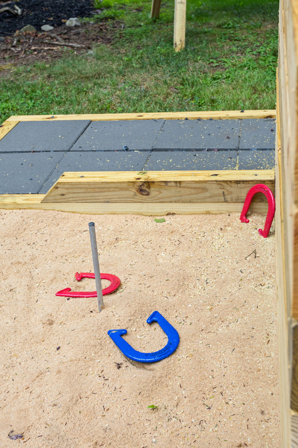 Classic Horseshoe Pit for Outdoor Fun – A well-maintained sandpit with a set of horseshoes, perfect for friendly outdoor competition in a rustic setting.