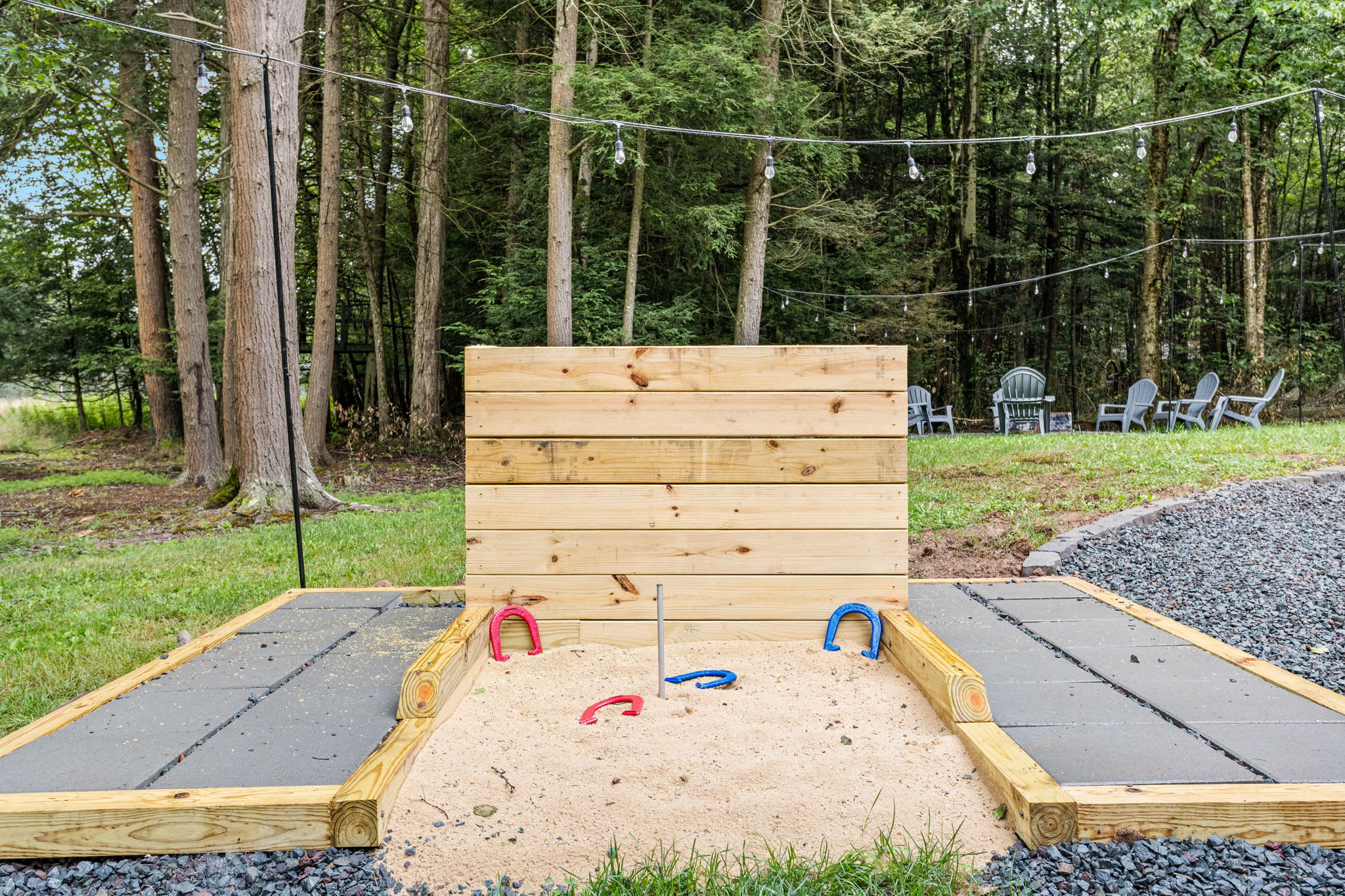 A thoughtfully designed horseshoe game setup with wooden backstops and gravel walkways, adding a fun touch to the outdoor space.