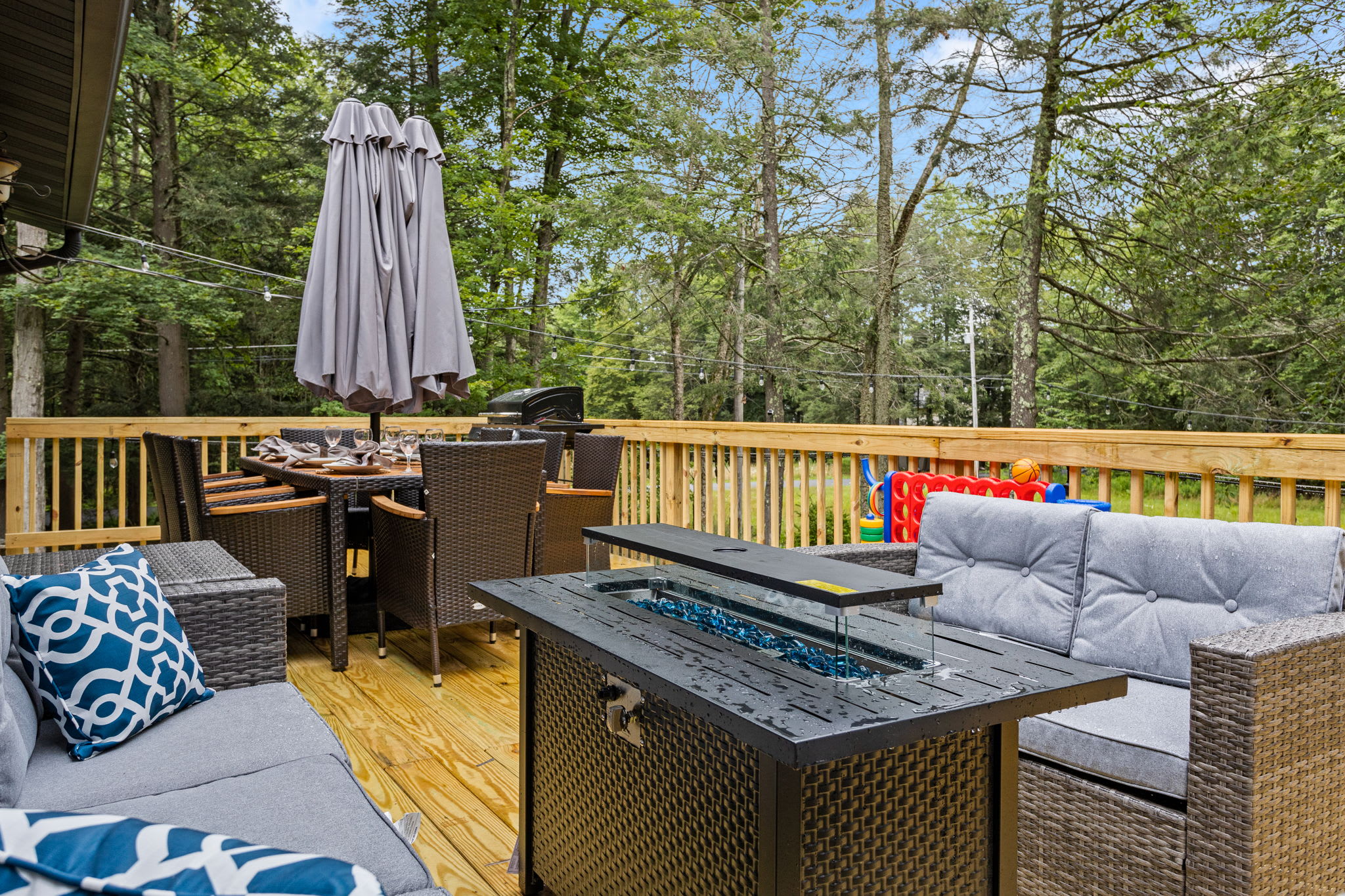 Cozy Outdoor Lounge & Fire Table – A beautifully designed deck space with plush seating, a fire table, and an umbrella for shade, creating a stylish and comfortable retreat.