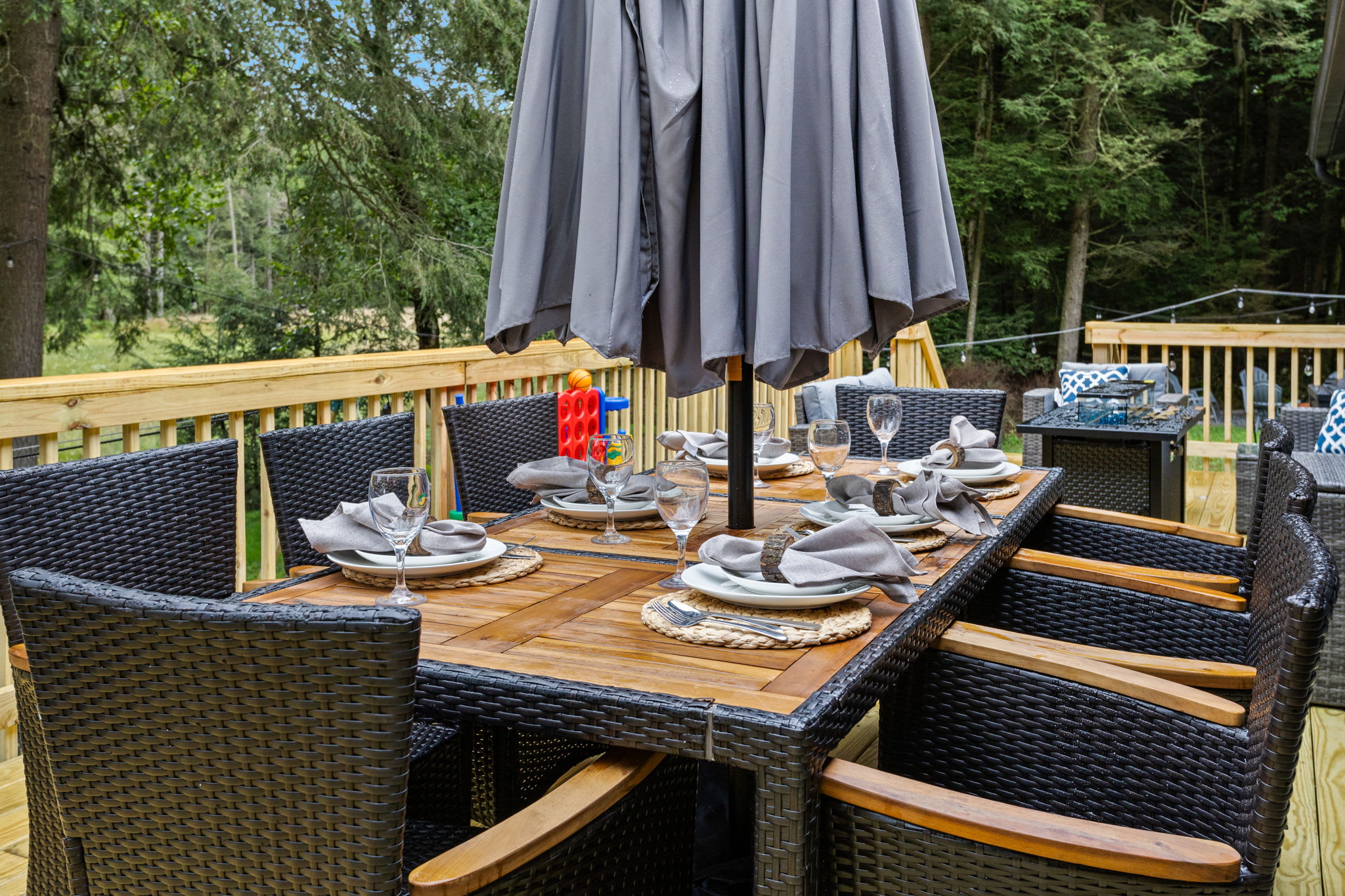 Elegant Outdoor Dining Experience – A stunning al fresco dining setup with a large table, comfortable seating, and an umbrella for shaded meals in a tranquil forest setting.