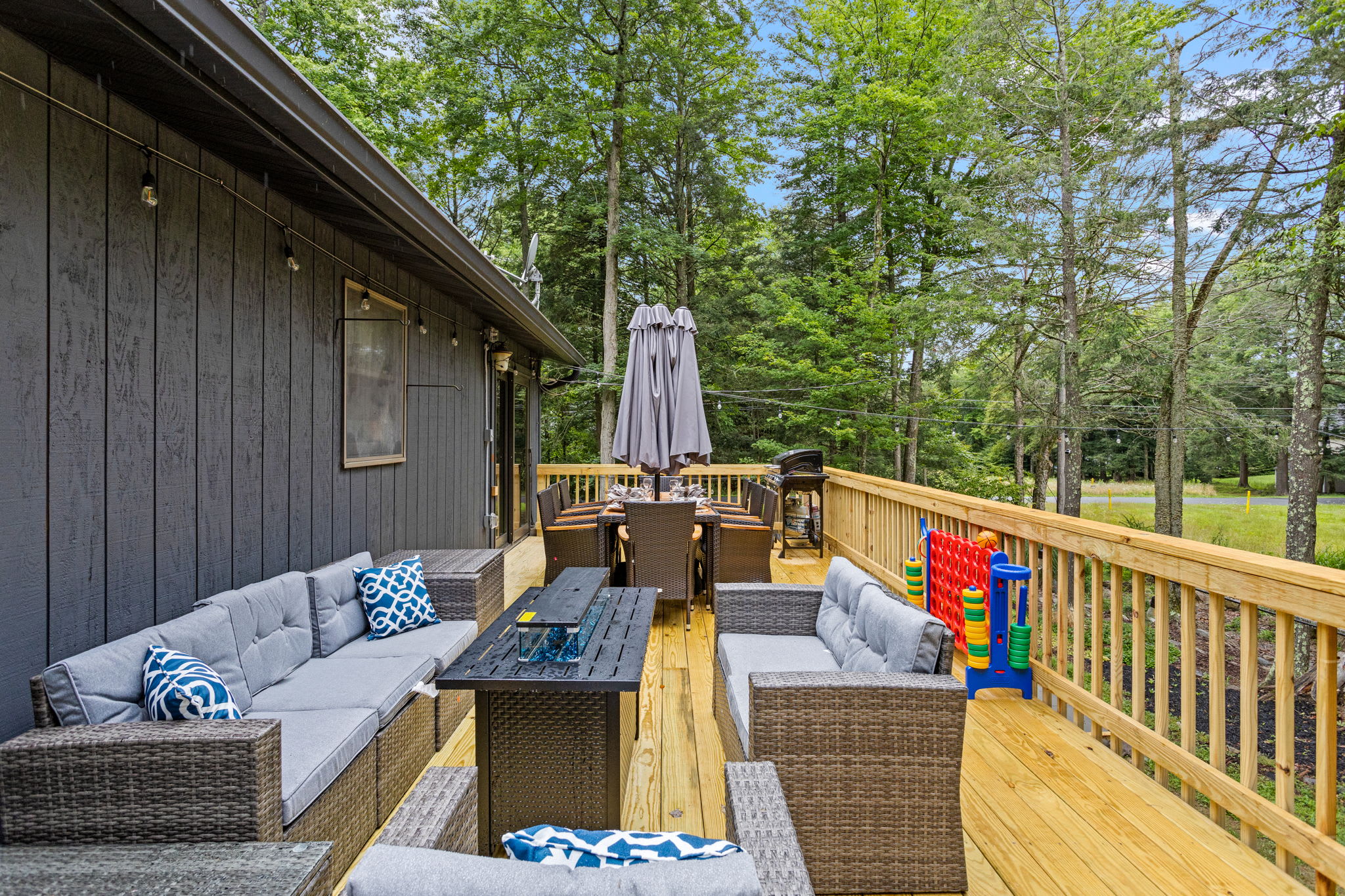 Spacious Wraparound Deck for Entertaining – A beautifully designed outdoor space with multiple seating areas, a fire table, and fun backyard games for guests to enjoy.