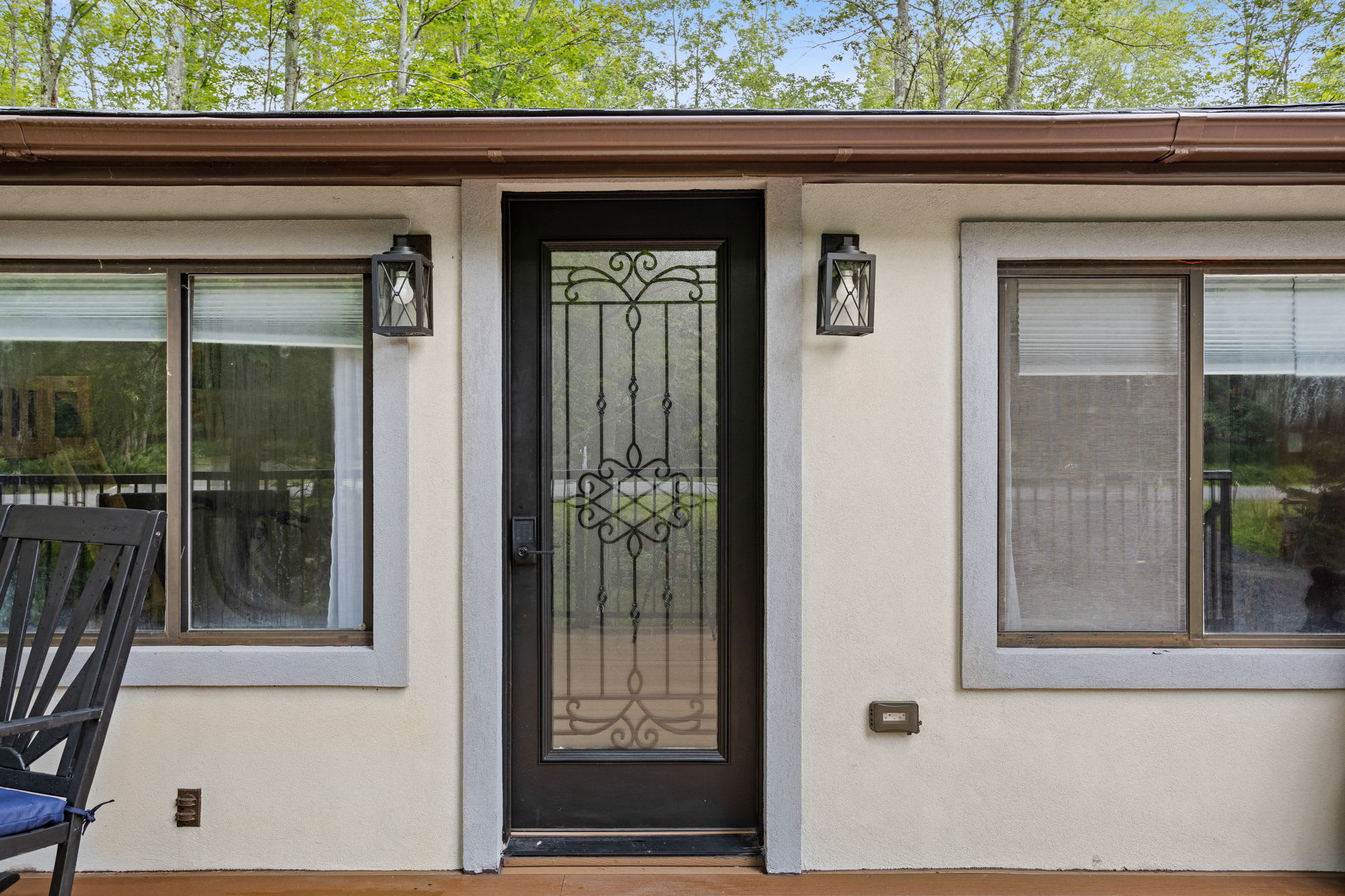 A charming entryway with a decorative glass door, framed by rustic lantern-style lighting. Step inside to find a cozy retreat that blends modern comfort with nature’s tranquility.