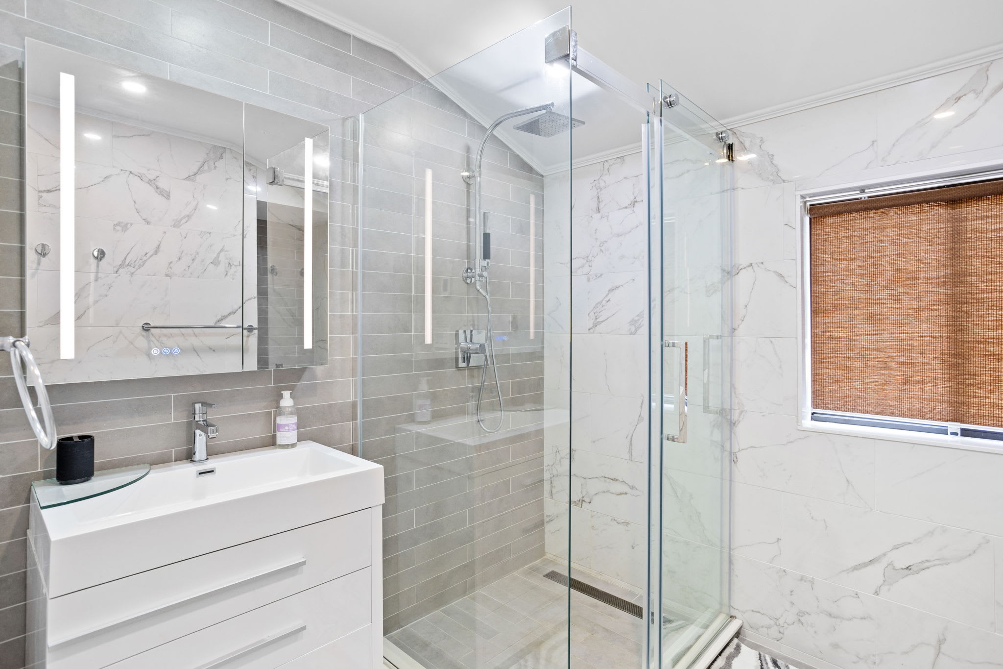 A stunning bathroom featuring a glass-enclosed rainfall shower, marble-inspired tiles, and modern fixtures for a spa-like experience.