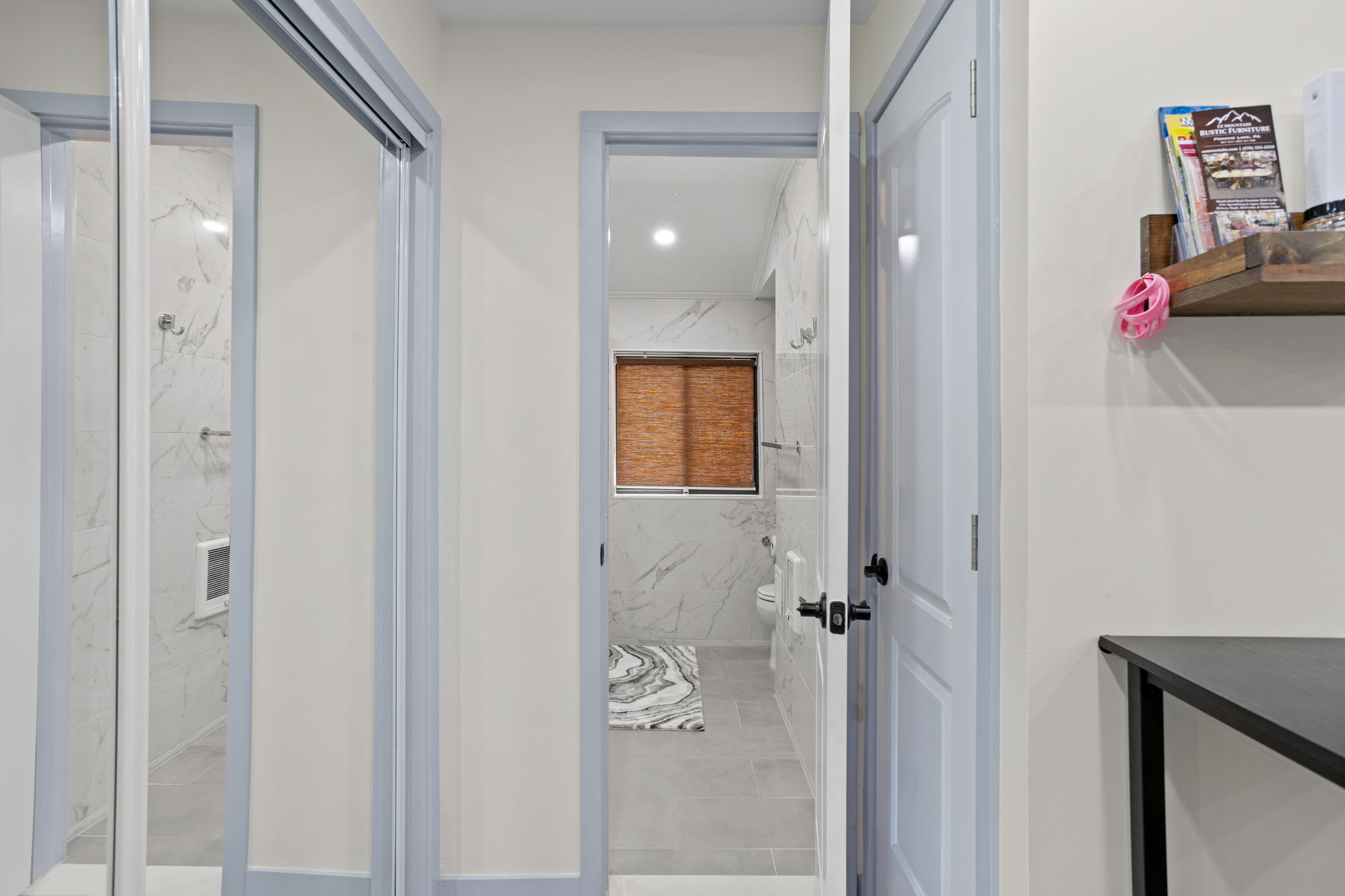 A clean, modern hallway leading to a spa-like bathroom, blending sleek design with calming tones for a relaxing retreat.
