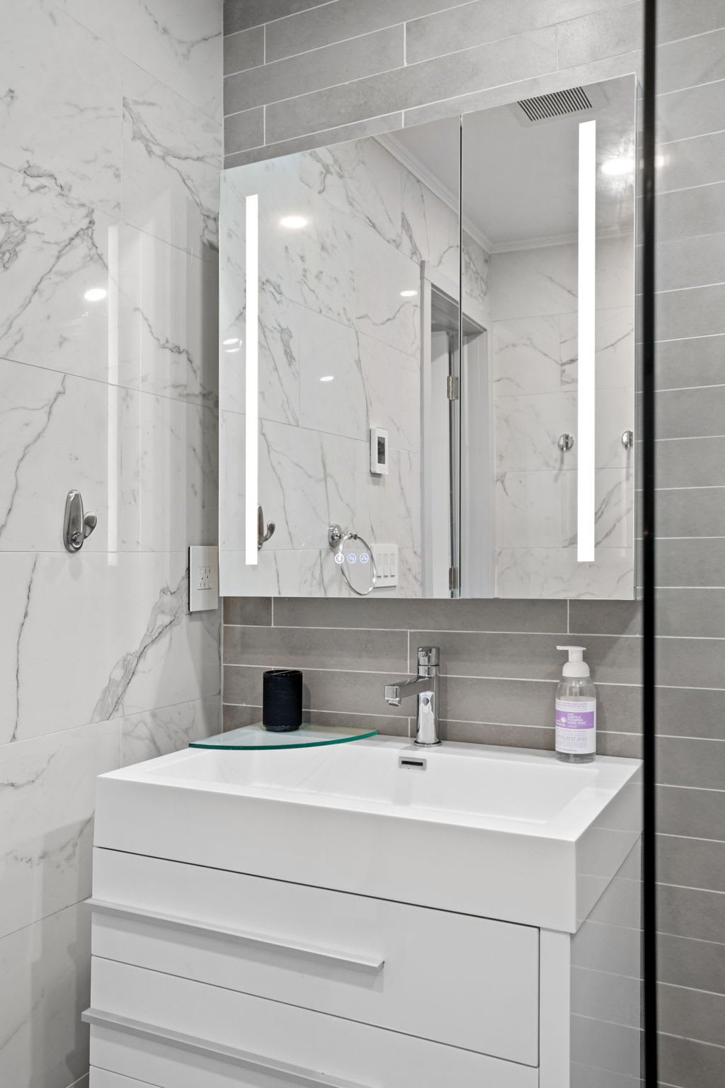 A minimalist yet stylish bathroom vanity with built-in lighting, a large mirror, and elegant finishes, creating a modern and refreshing space.