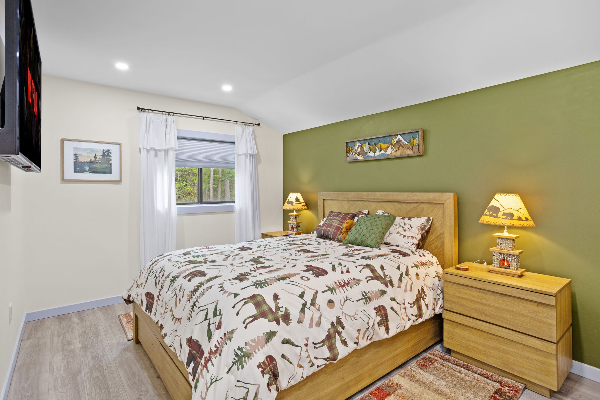 Wake up to the soft glow of natural light in this peaceful bedroom, complete with a plush bed, rustic accents, and a view of the serene outdoors.