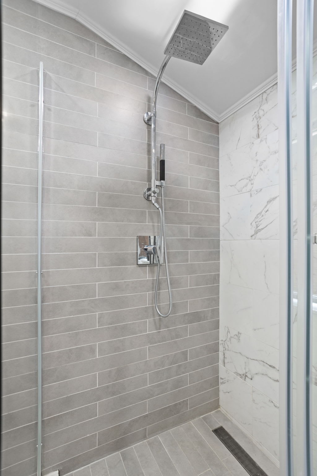 Step into luxury with this modern rainfall shower, featuring a glass enclosure, elegant gray tiling, and a spa-like ambiance perfect for relaxation.