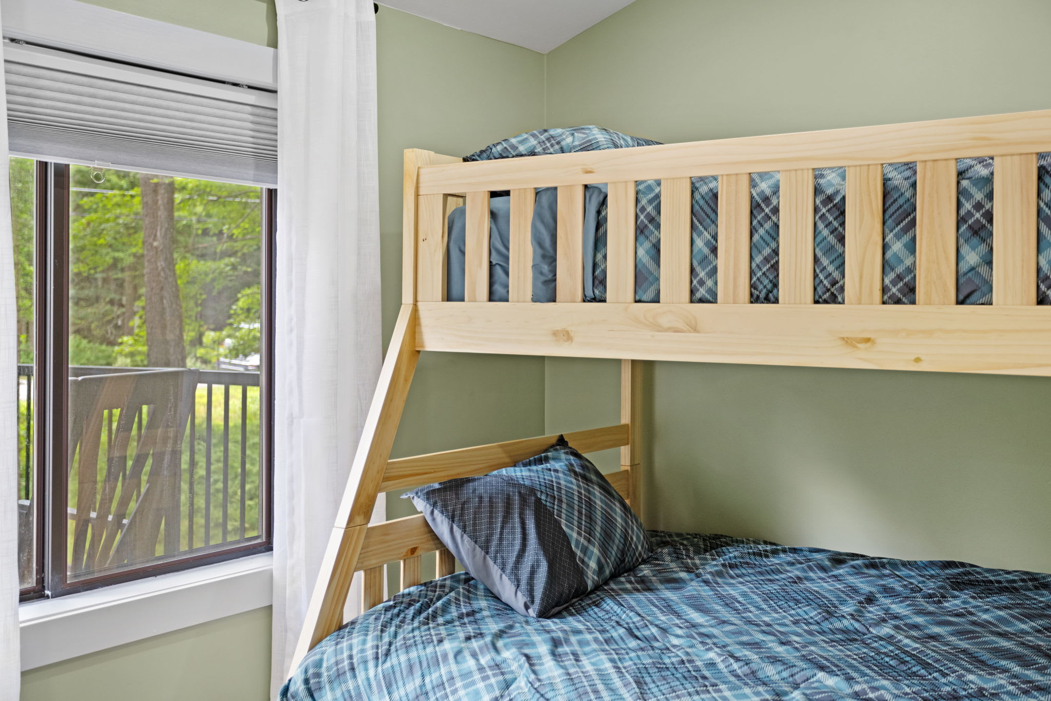 A cozy and fun sleeping arrangement, this sturdy wooden bunk bed is perfect for families or groups, with a window view bringing in plenty of natural light.