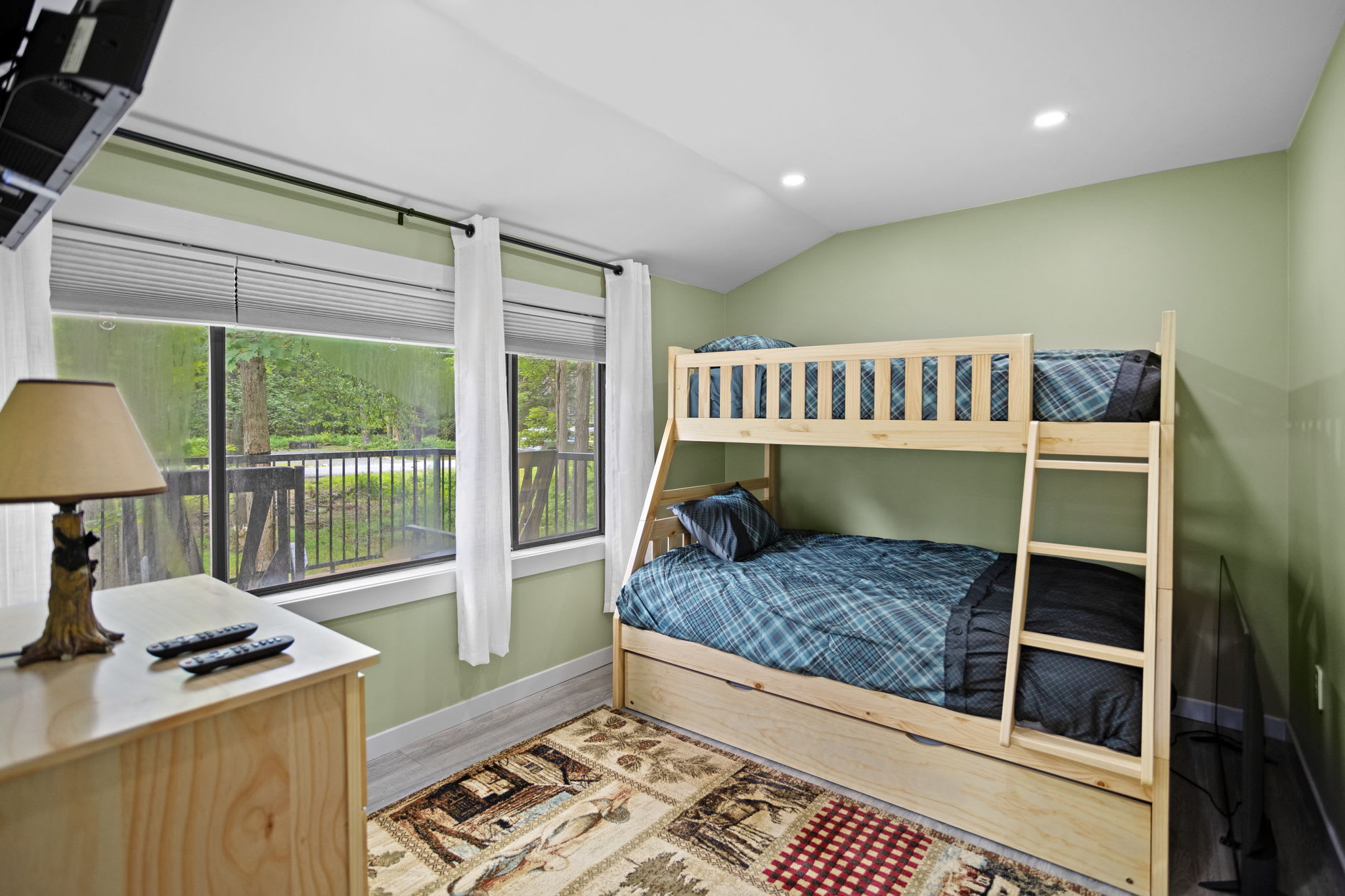 A warm and inviting bunk room with ample space, cozy bedding, and large windows that let in plenty of fresh air and natural light.