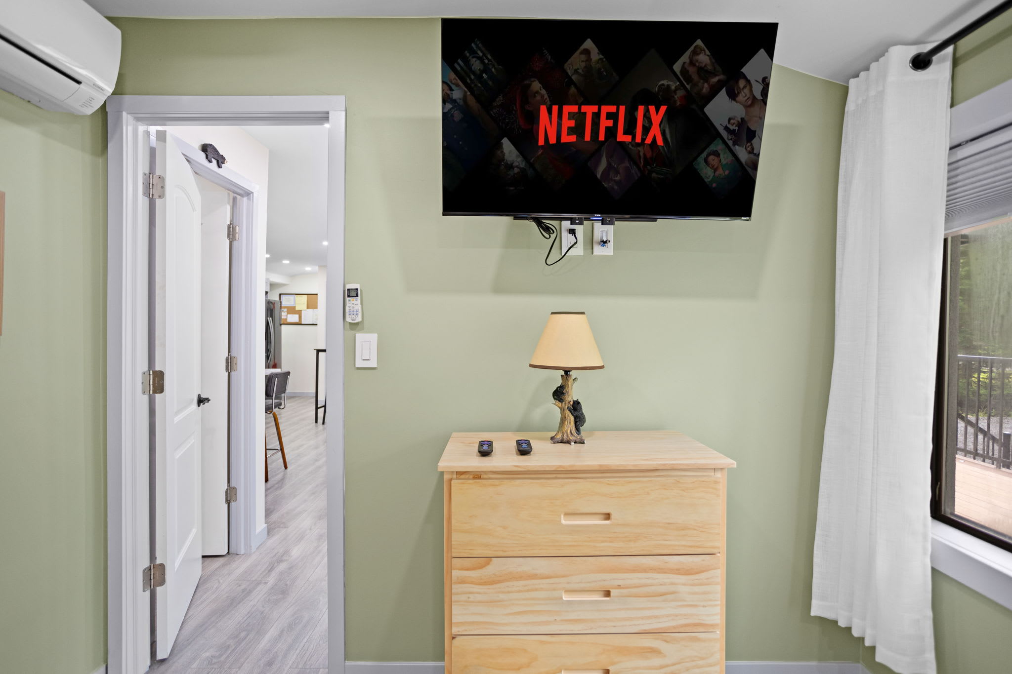 Enjoy movies or shows from the wall-mounted TV in this charming bunk room. The mix of rustic and modern elements makes it both cozy and functional.