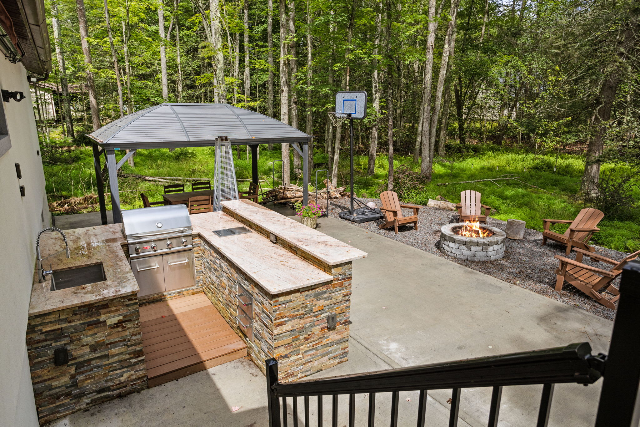 Step into your private backyard retreat, complete with a fully equipped outdoor kitchen, a gazebo for shaded lounging, and a firepit surrounded by Adirondack chairs, perfect for cozy nights under the stars.