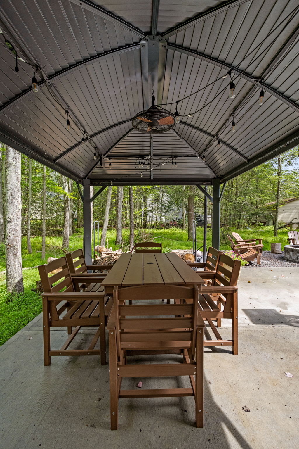 Gather around this long wooden dining table and enjoy meals in a peaceful outdoor setting, surrounded by towering trees and fresh air.