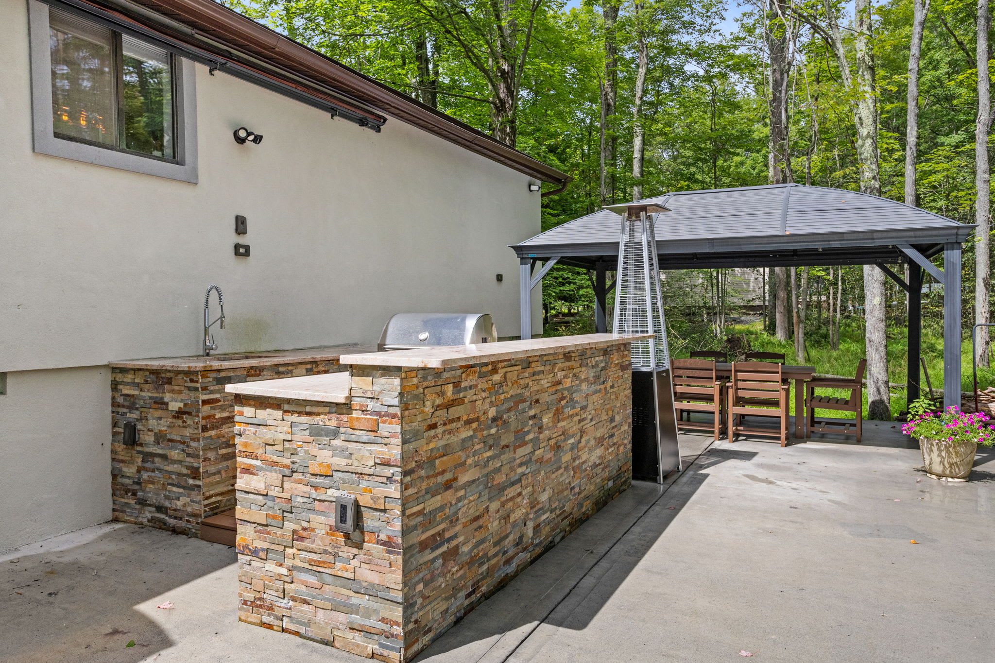 Whether you're mixing up drinks or grilling dinner, this beautifully designed stone bar and kitchen area make outdoor entertaining effortless and stylish.
