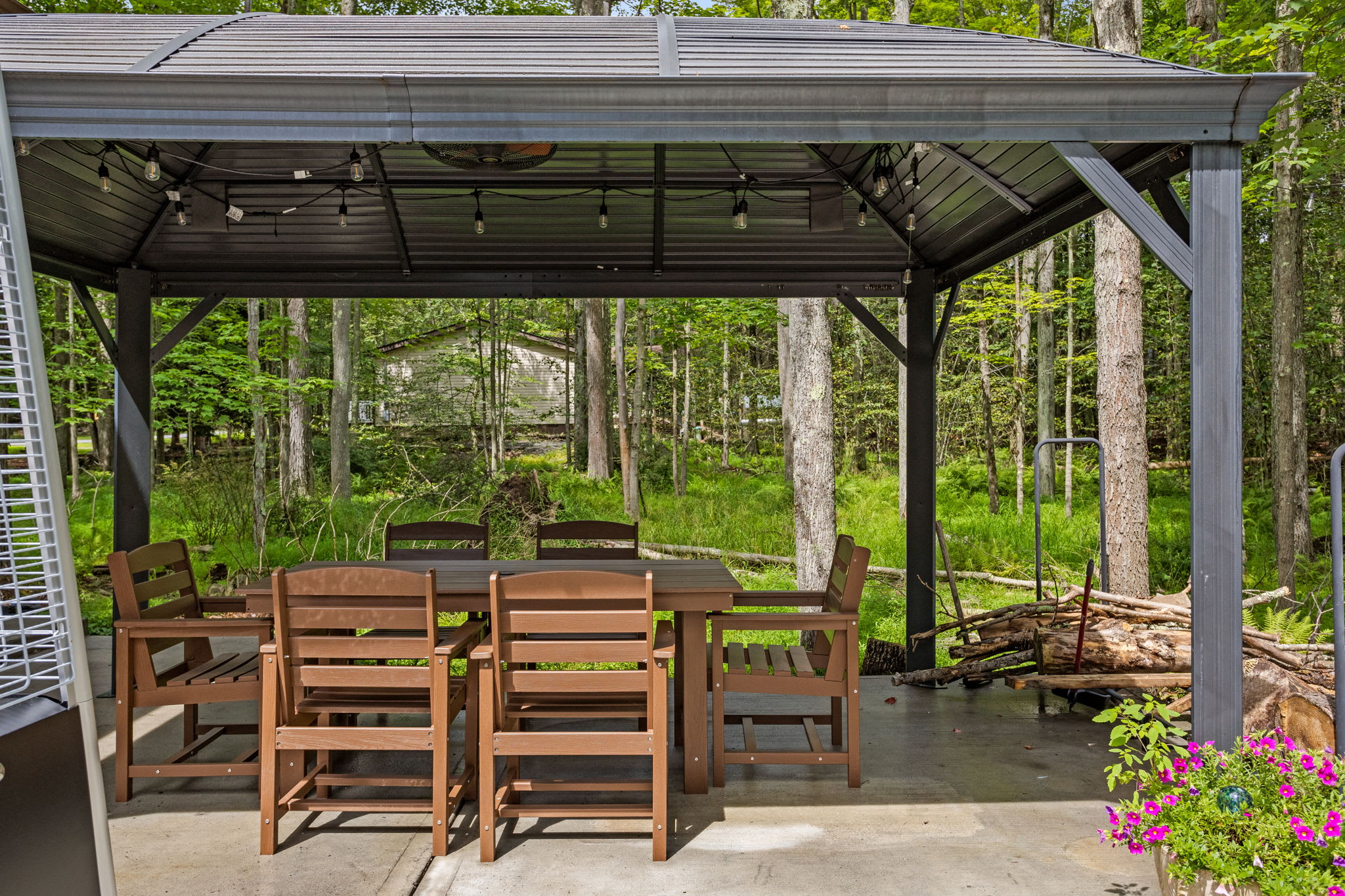 Dine in comfort under this large, modern gazebo, complete with string lights and a fan to keep you cool on warmer days.