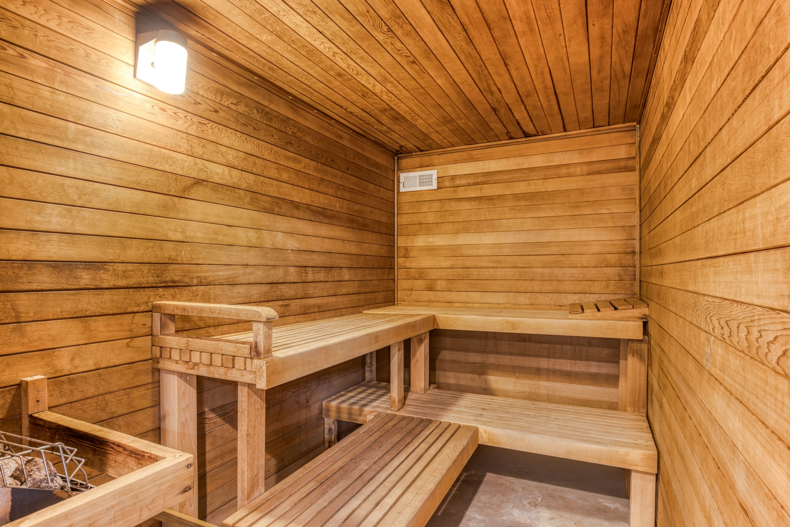 A warm and inviting sauna room, fully paneled in light-toned wood, featuring multi-tiered wooden benches for relaxation.
