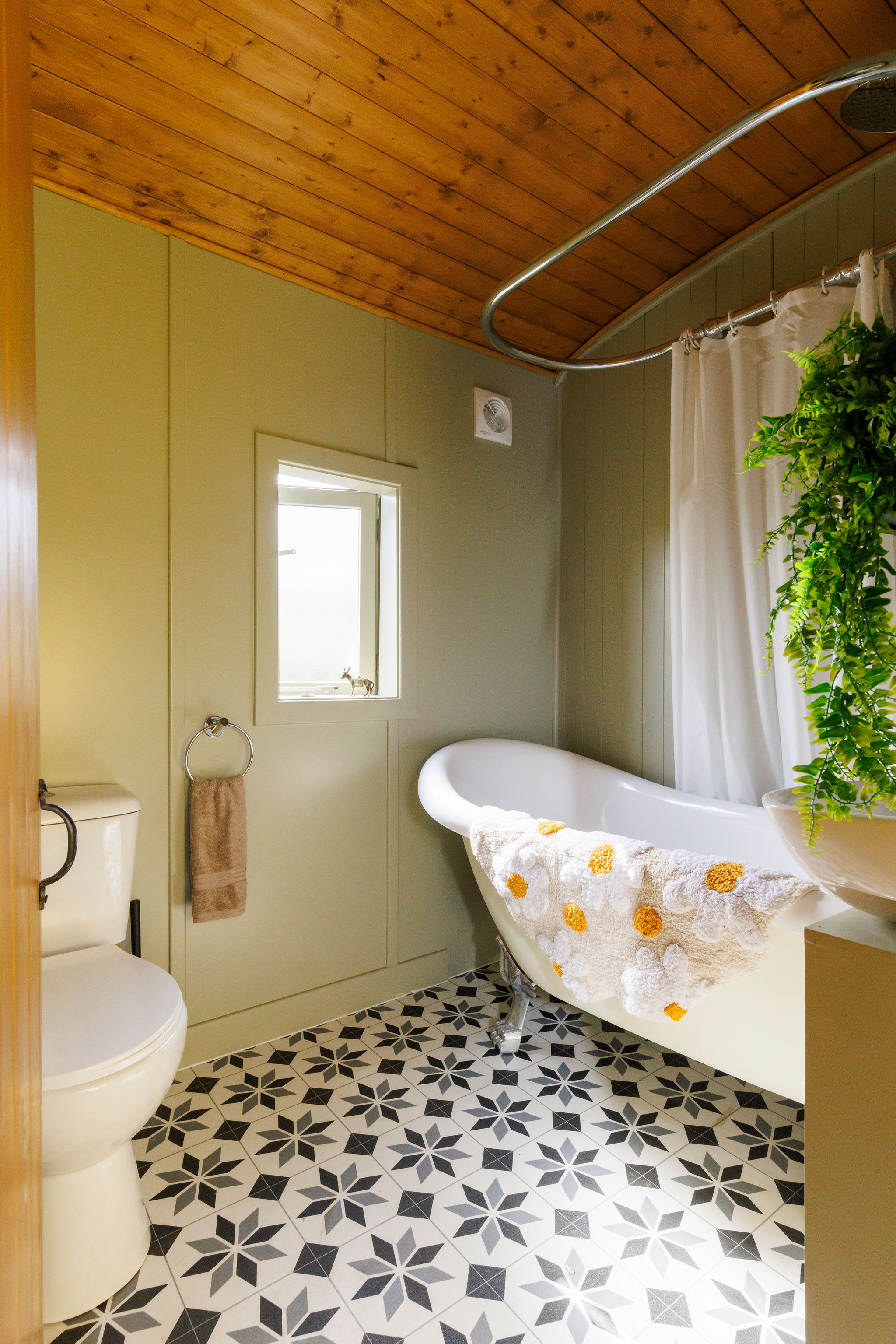 The bathroom has a roll top bath, overhead shower, WC and sink.