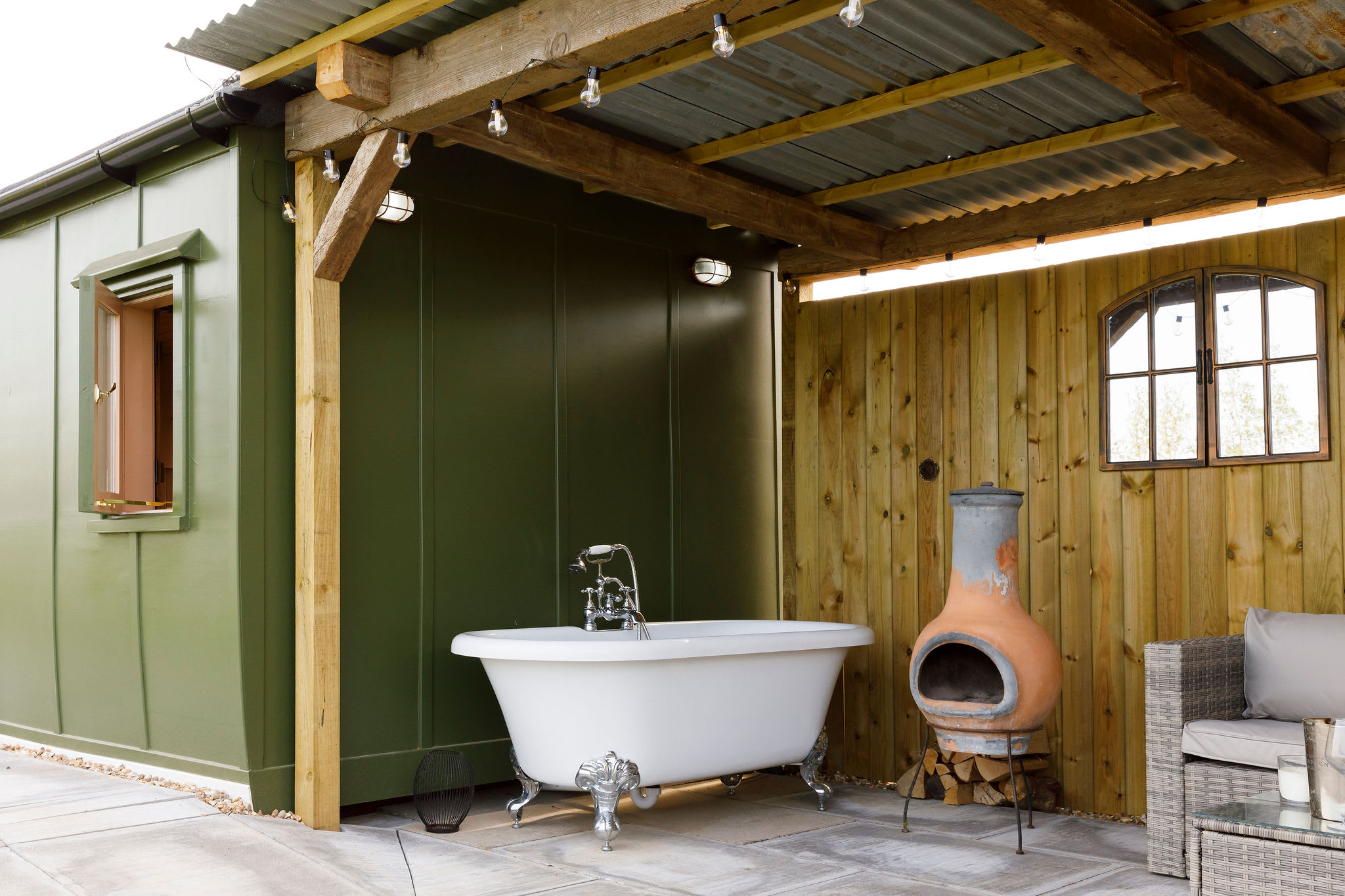 Unwind in the sheltered outdoor seating area, featuring a rustic fireplace and a classic bathtub. Perfect for starry night relaxation