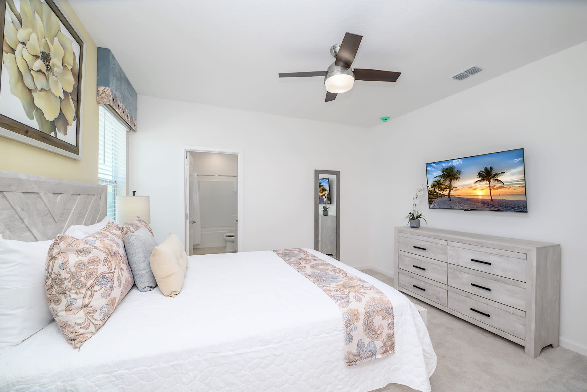 Bright Bedroom Featuring A Queen-Sized Bed And Floral Decor Accents