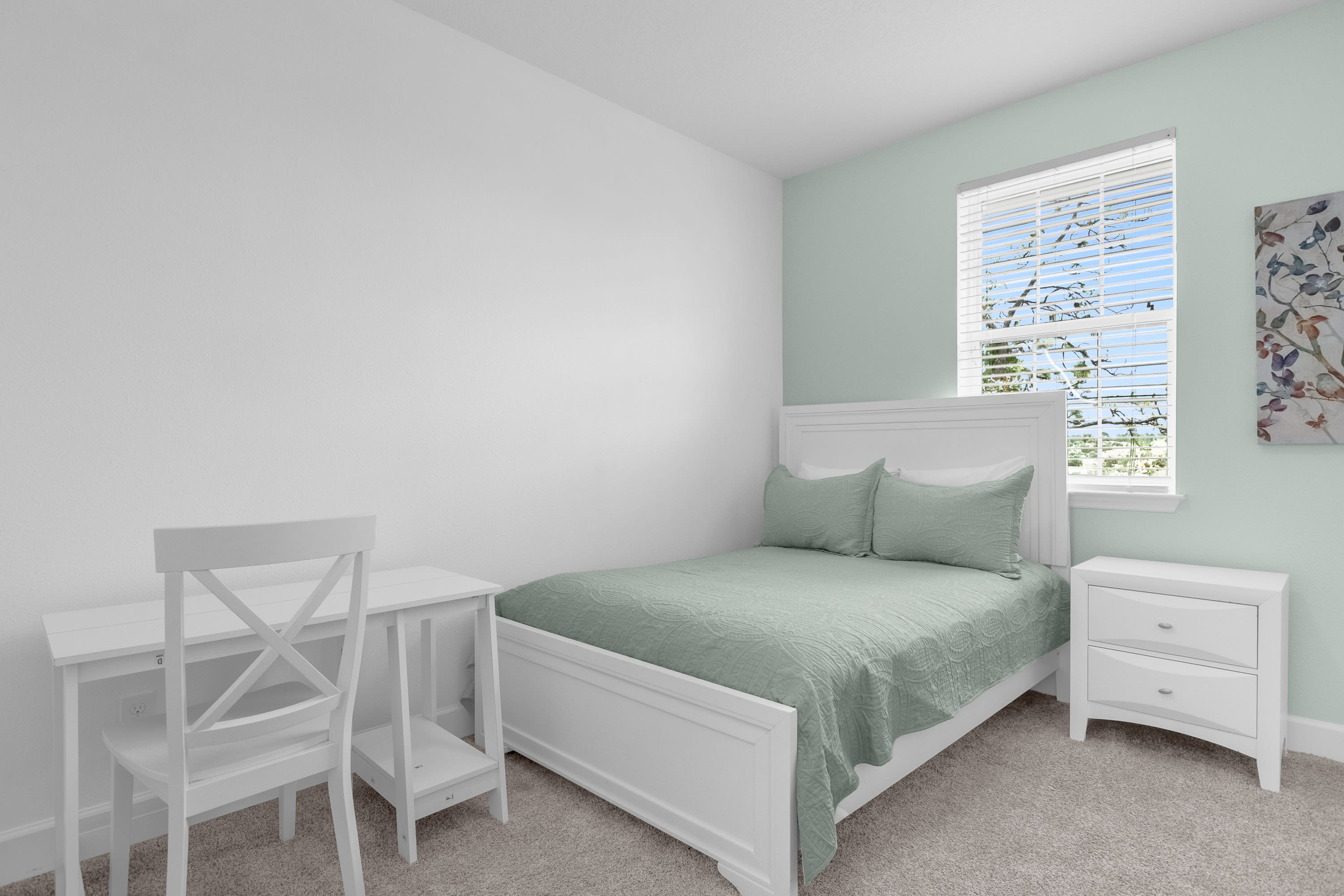 Bright Bedroom Featuring A Desk Area And Soft Green Decor