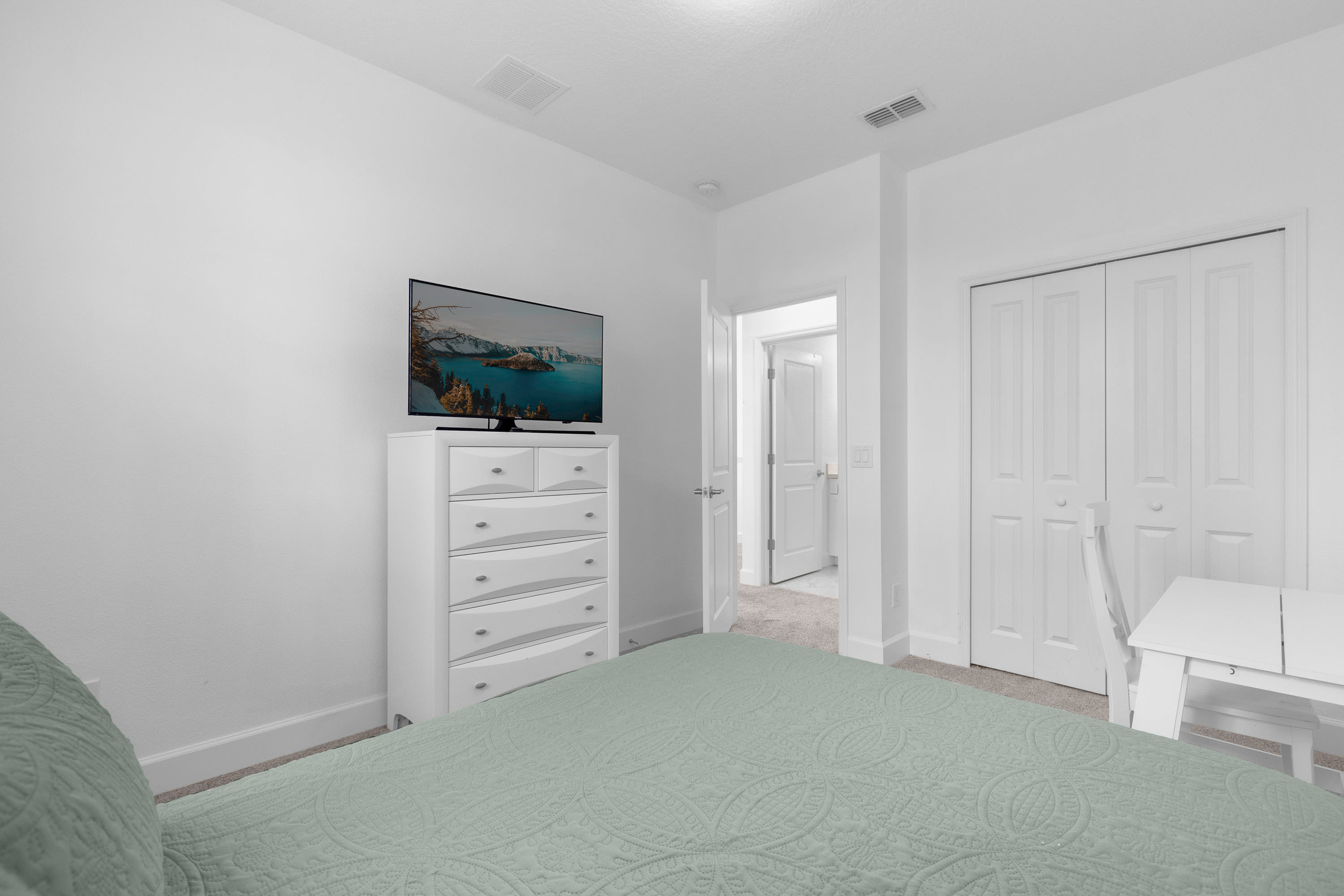 Modern Bedroom Featuring A Wall-Mounted TV And Soft Green Hues