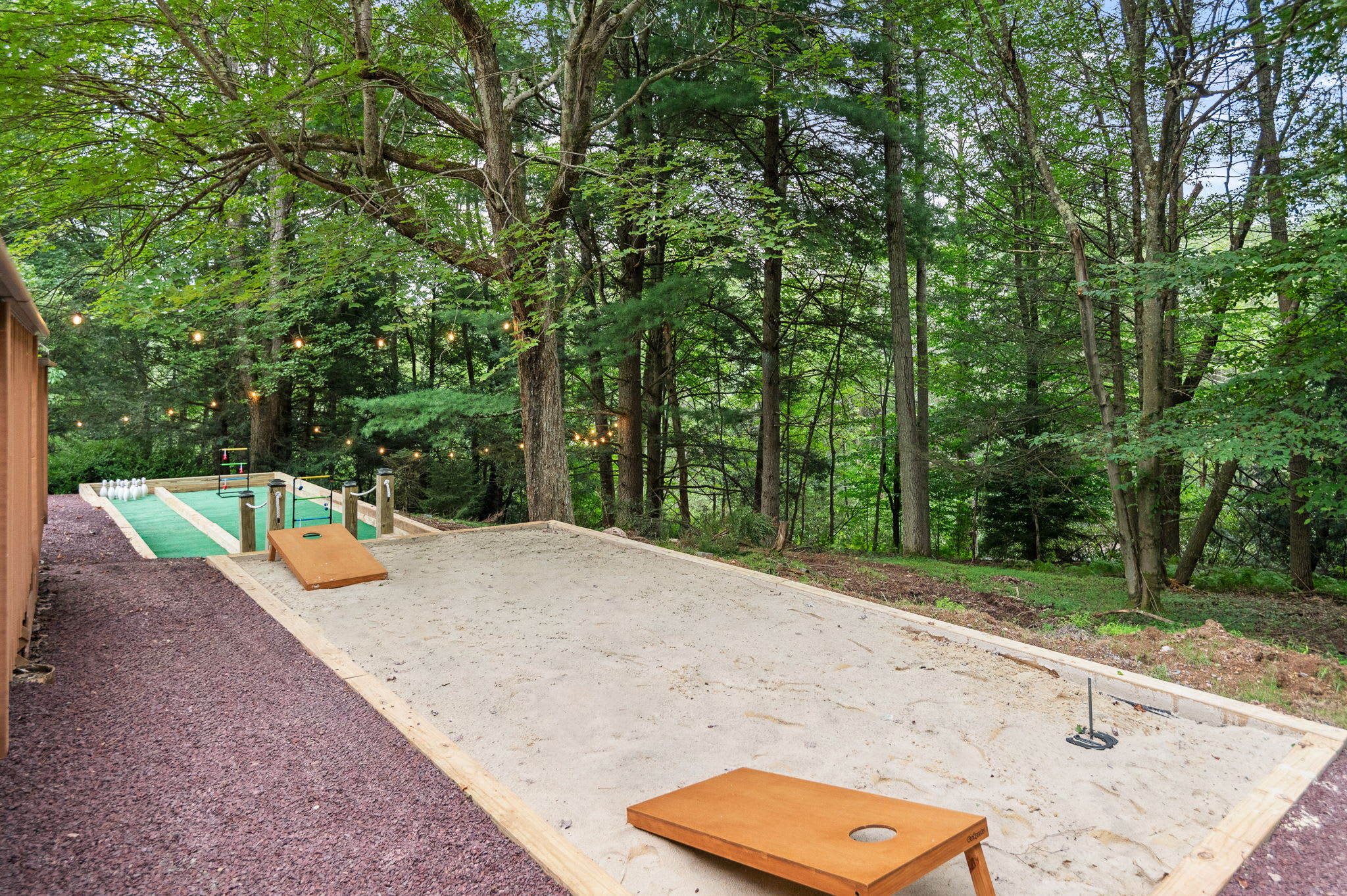 Play cornhole or horseshoes on this dedicated outdoor game area surrounded by nature and string lights for evening fun.