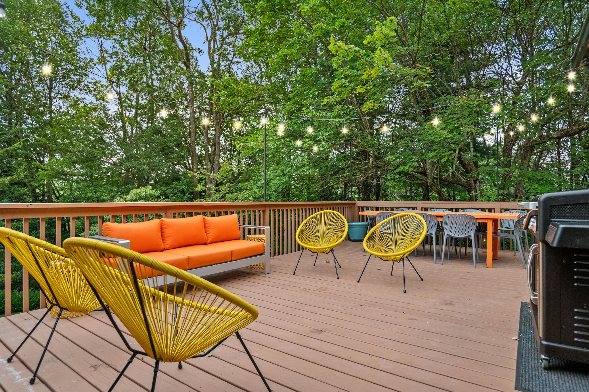 String lights, vibrant seating, and an inviting deck make this the ideal spot for an alfresco meal with friends and family.