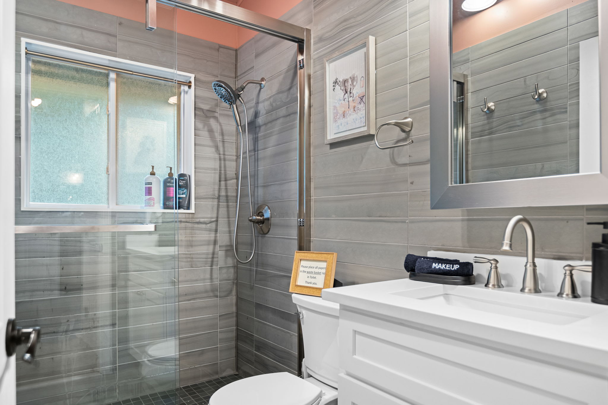 This modern bathroom features a sleek glass shower, wood-inspired tiling, and soft lighting for a refreshing and luxurious experience.