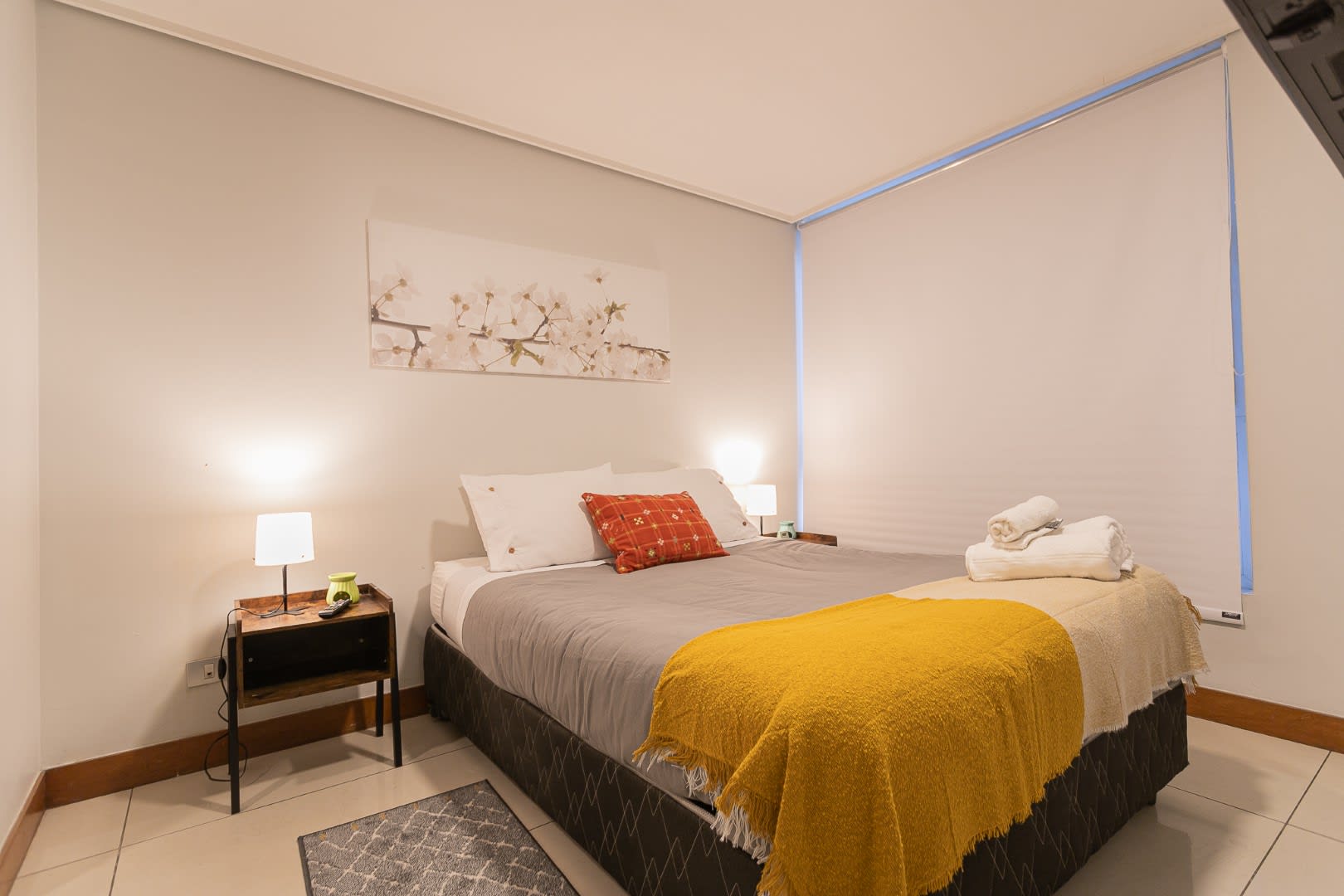 Relax in comfort with our king-sized bed, featuring soft gray bedding and a vibrant yellow throw for a touch of warmth.