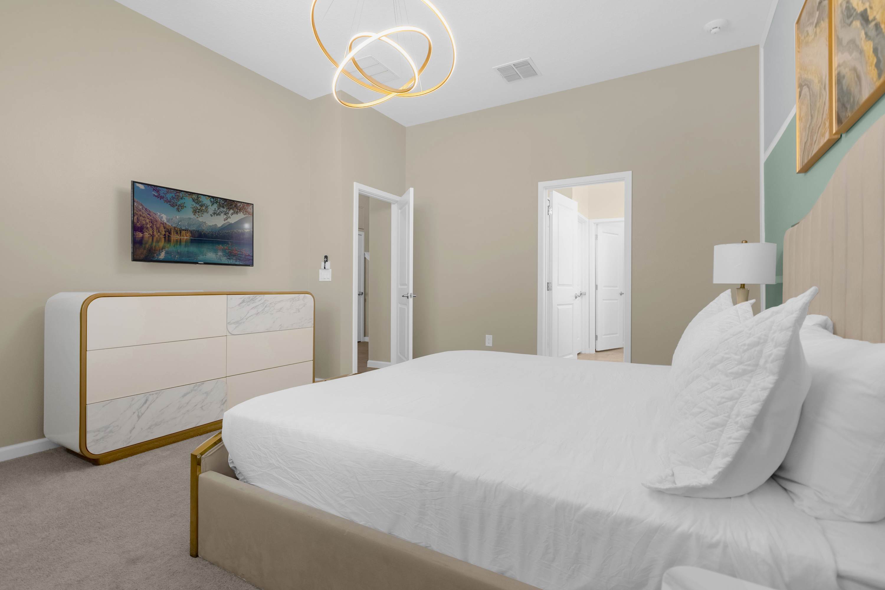 Luxurious Bedroom With A King Bed Featuring Vibrant Wall Art And A Smart TV