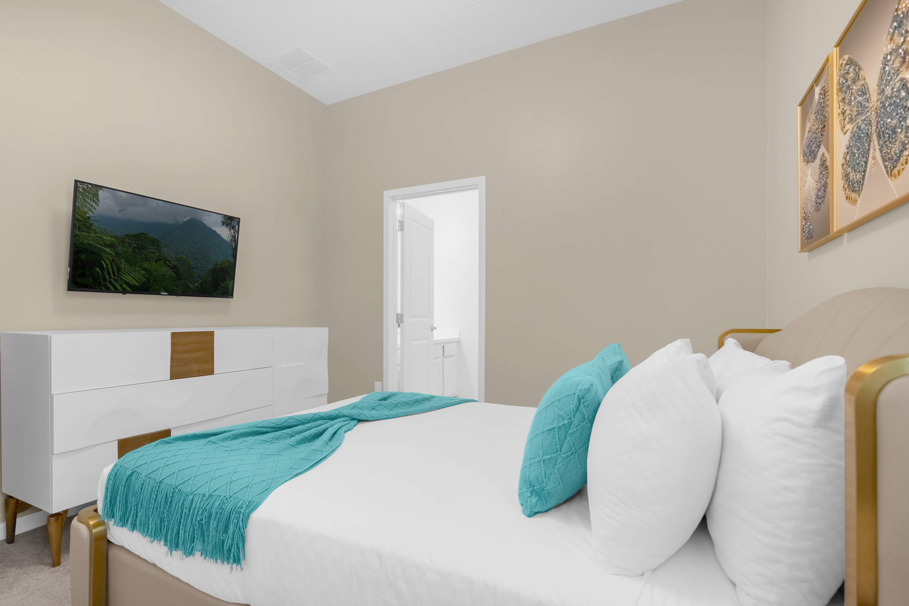 Elegant Bedroom With A Queen Bed, Colorful Wall Decor, And A Smart TV