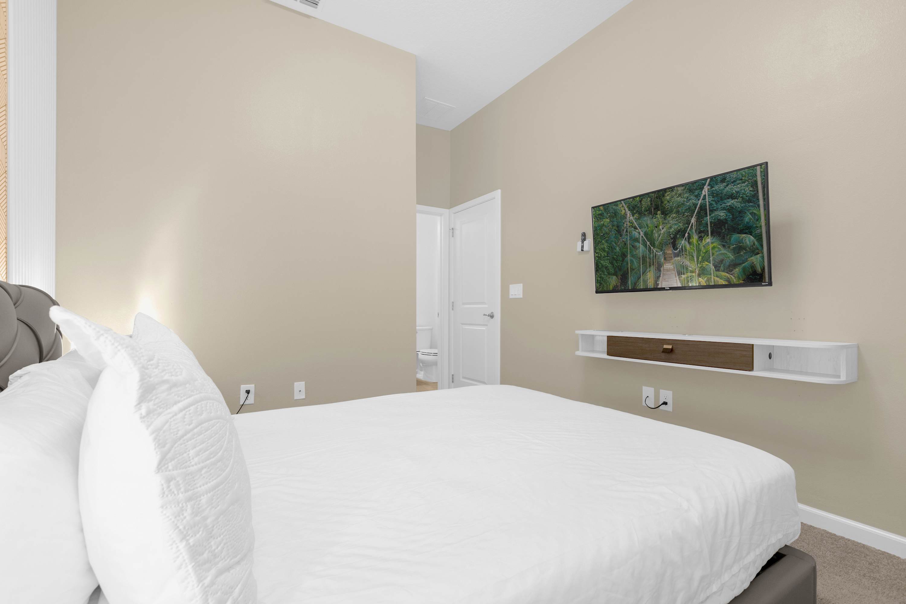 Elegant Bedroom With A Queen Bed, Colorful Wall Decor, And A Smart TV