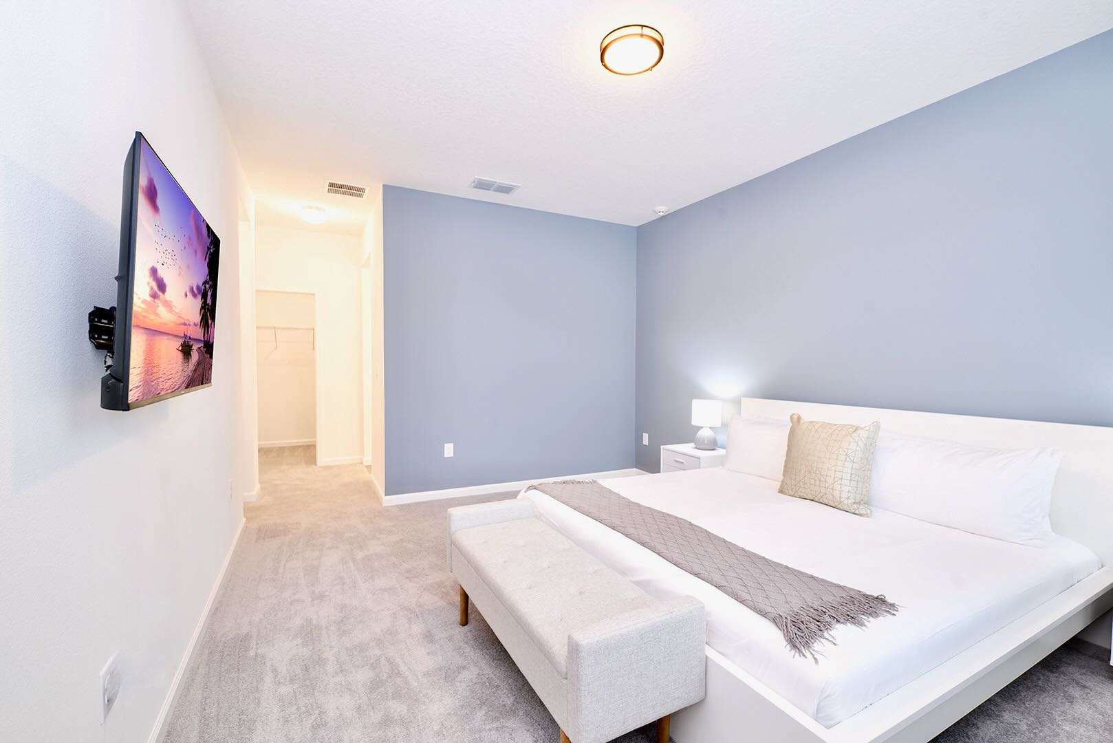 Spacious Bedroom With Soft Blue Accents And Smart TV For Relaxation